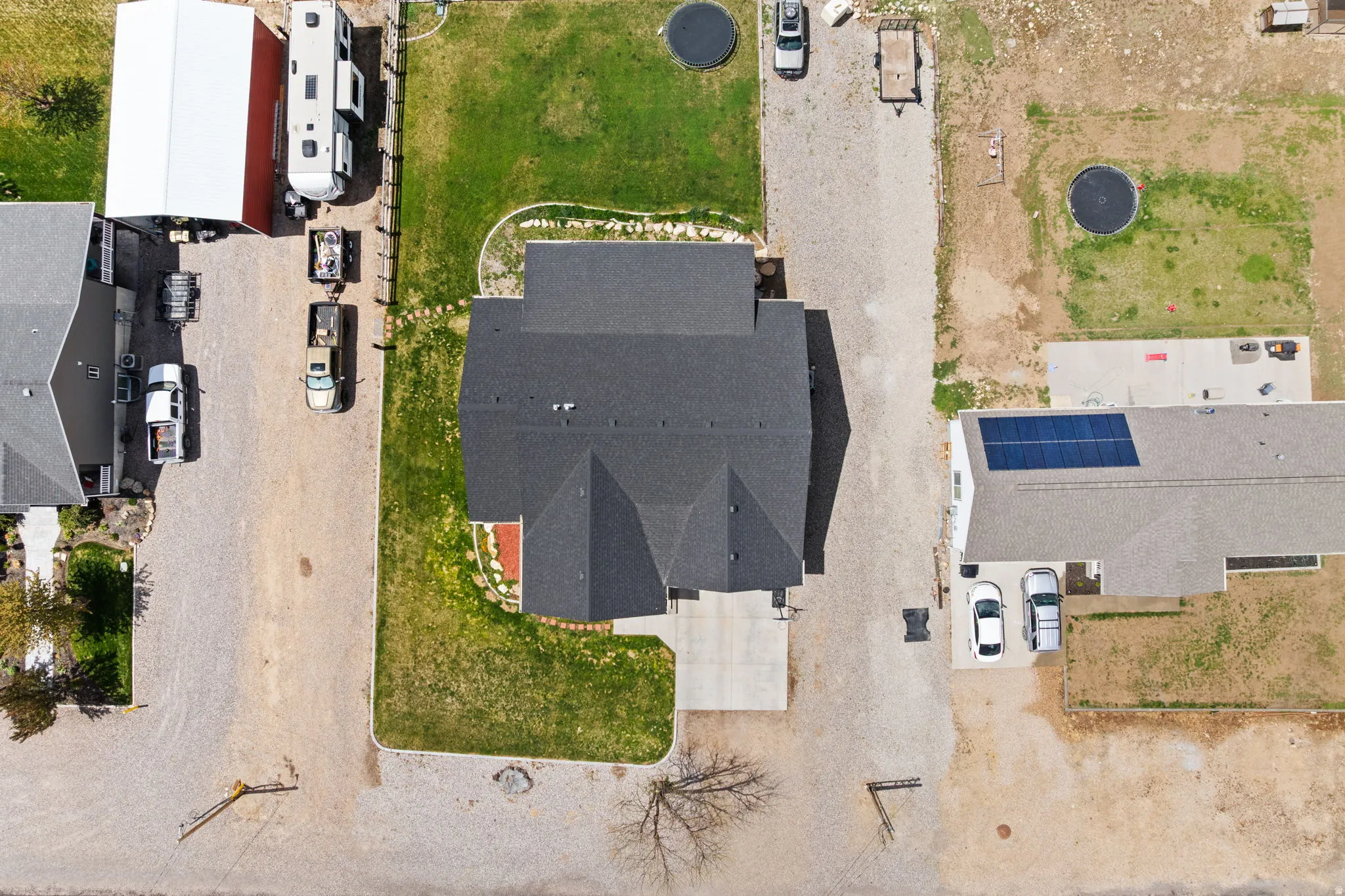 Aerial view showcasing a property with a dark shingle roof and a concrete driveway