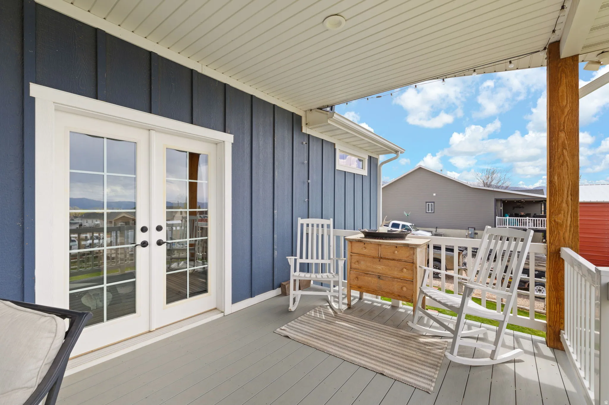 Covered porch with board and batten siding, painted wood flooring, white railing, and a wood support column