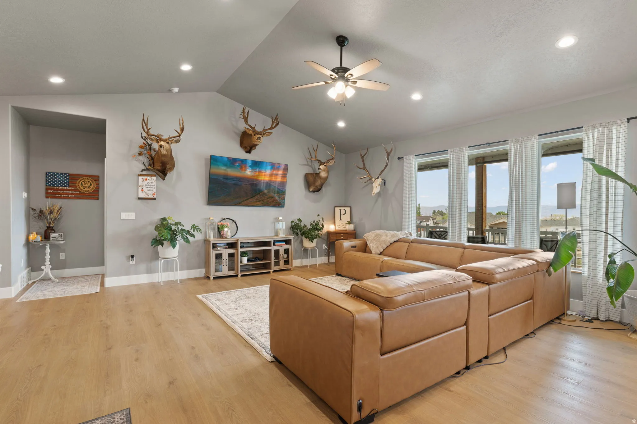 Open-concept living space featuring wood-finish flooring, vaulted ceilings, recessed lighting, and a ceiling fan