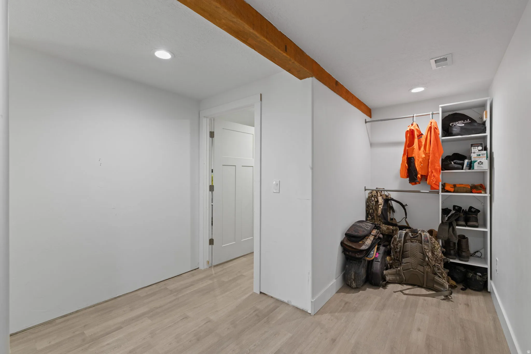 Recessed lighting illuminates wood-finish flooring and white walls