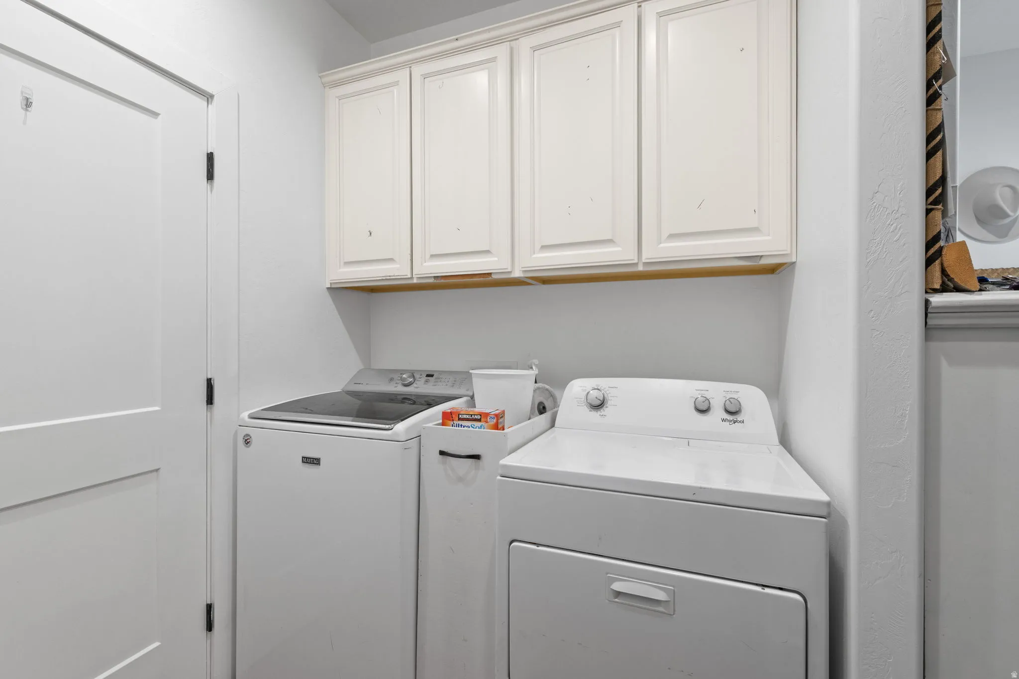 Laundry area featuring white cabinetry, a built-in shelf, and a white paneled door