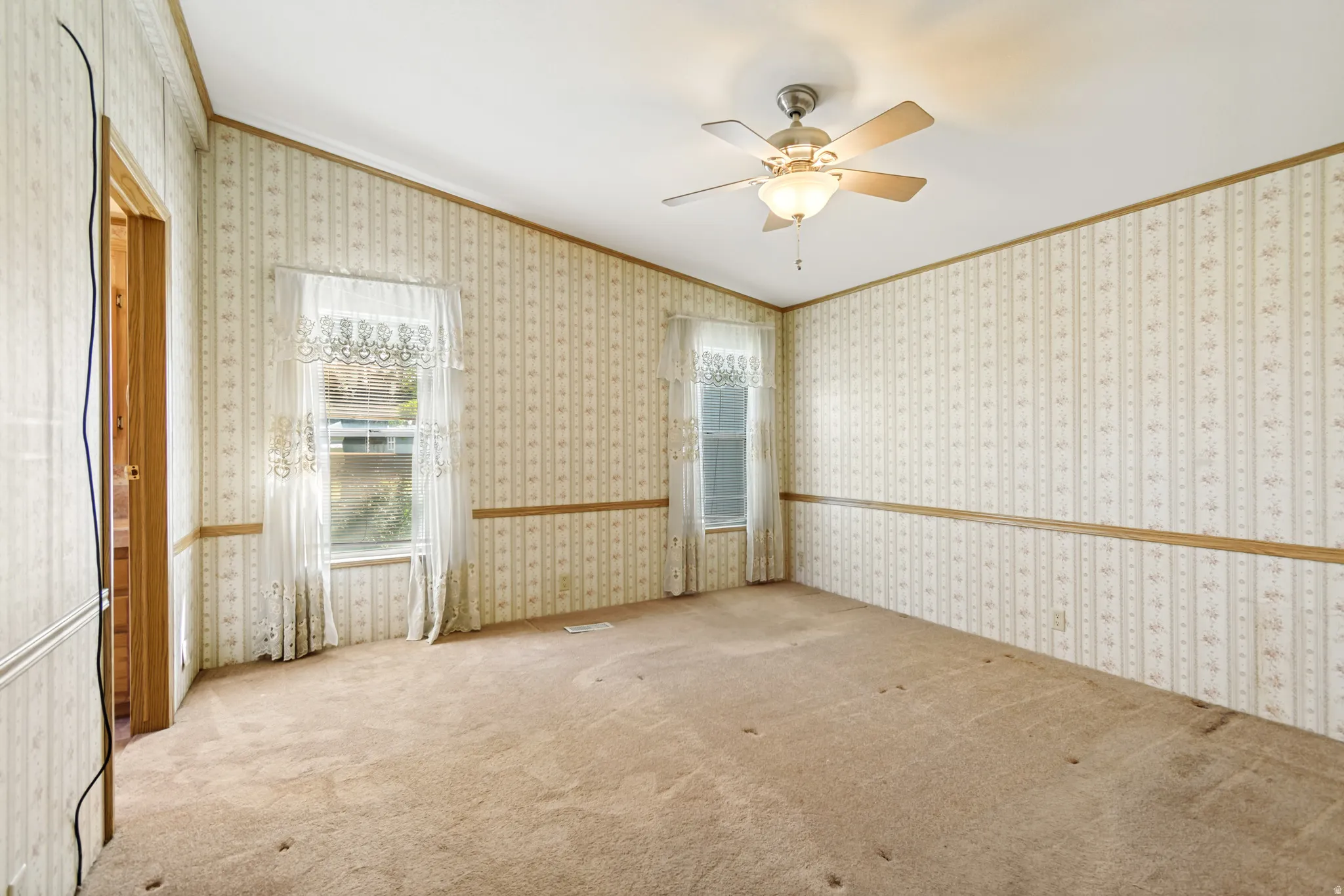 Carpeted spare room with ornamental molding, ceiling fan, and wallpapered walls