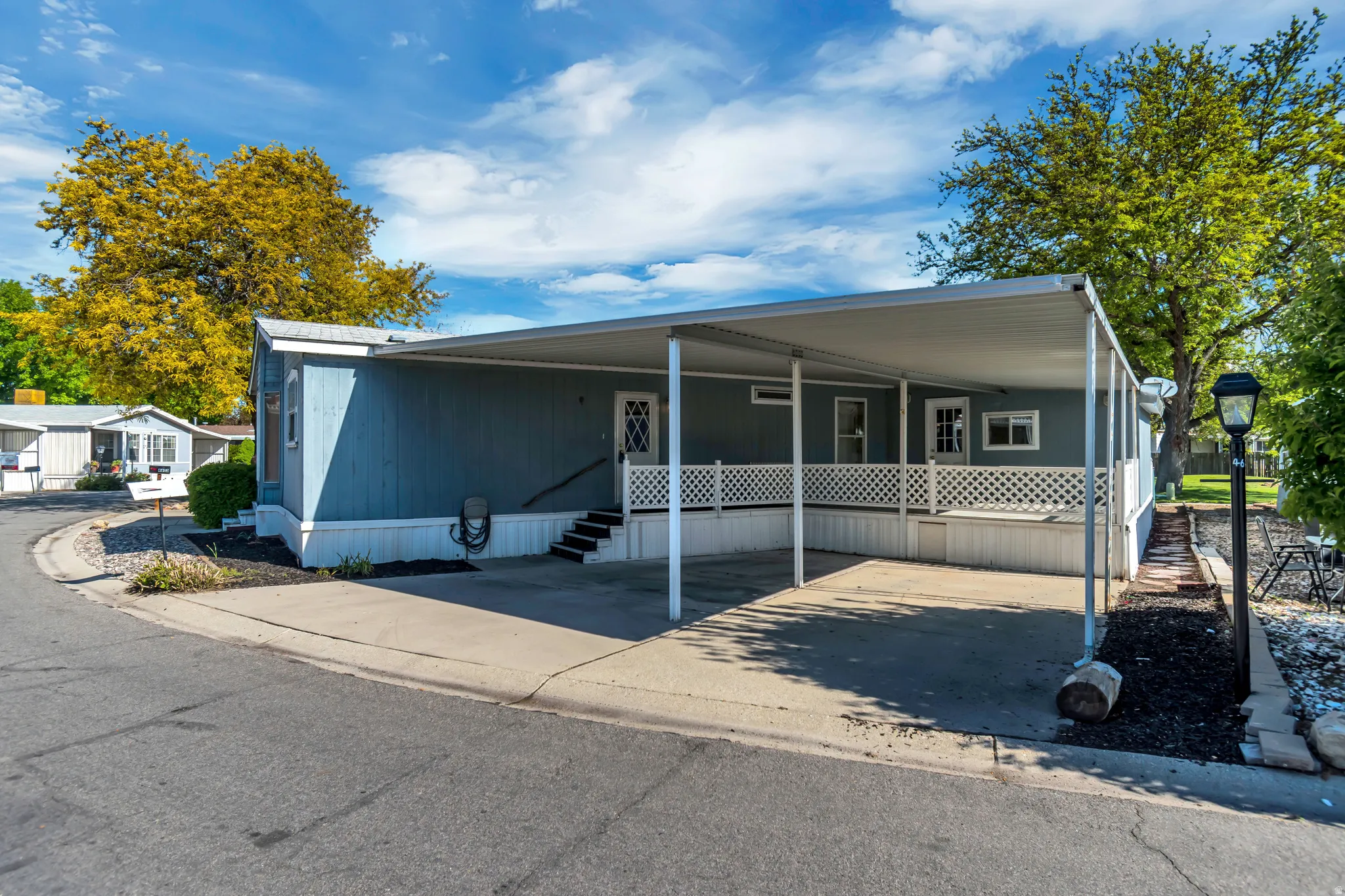 Manufactured / mobile home featuring a porch, a carport, entry steps, and concrete driveway