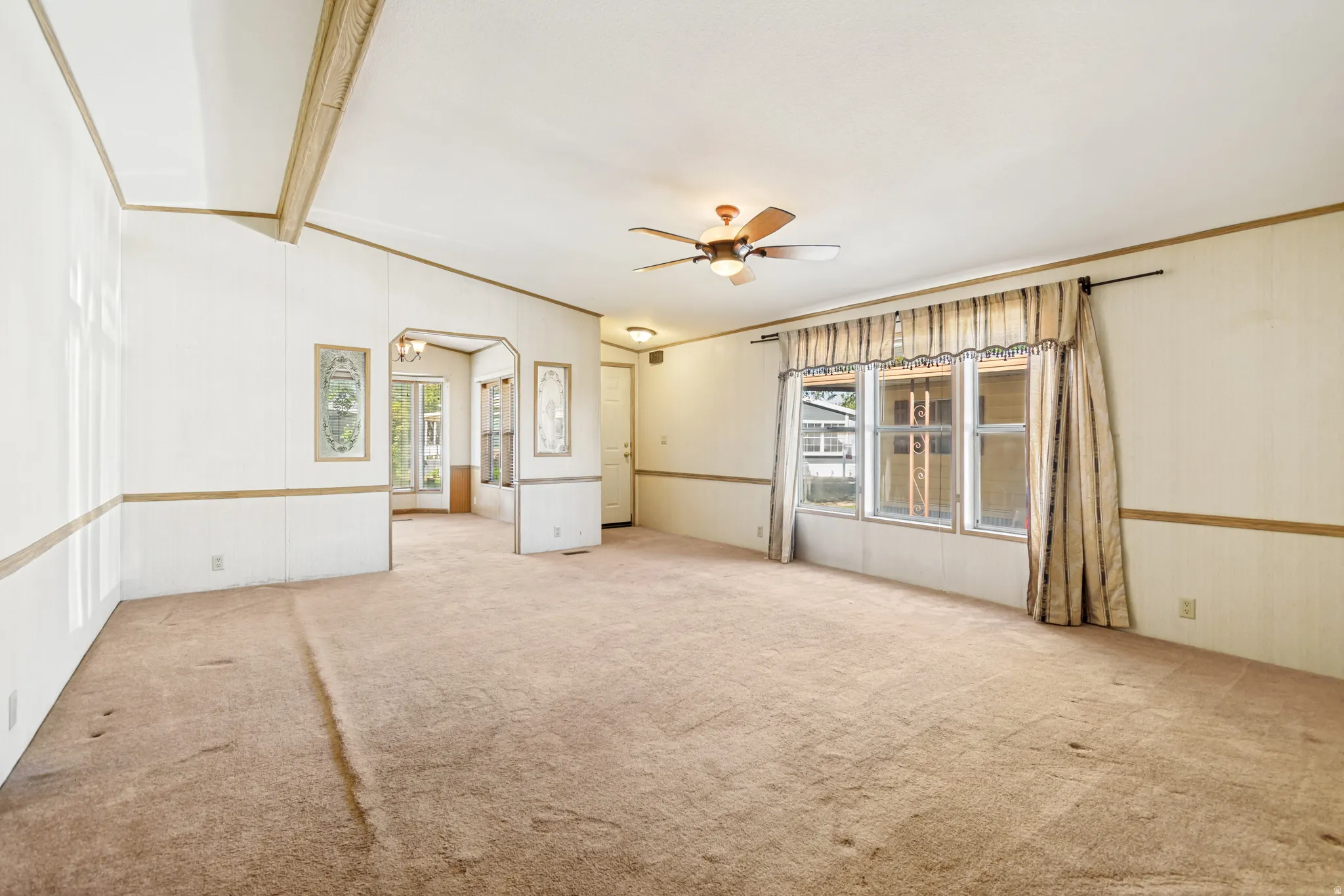 Spare room featuring light colored carpet, ceiling fan, beamed ceiling, and crown molding