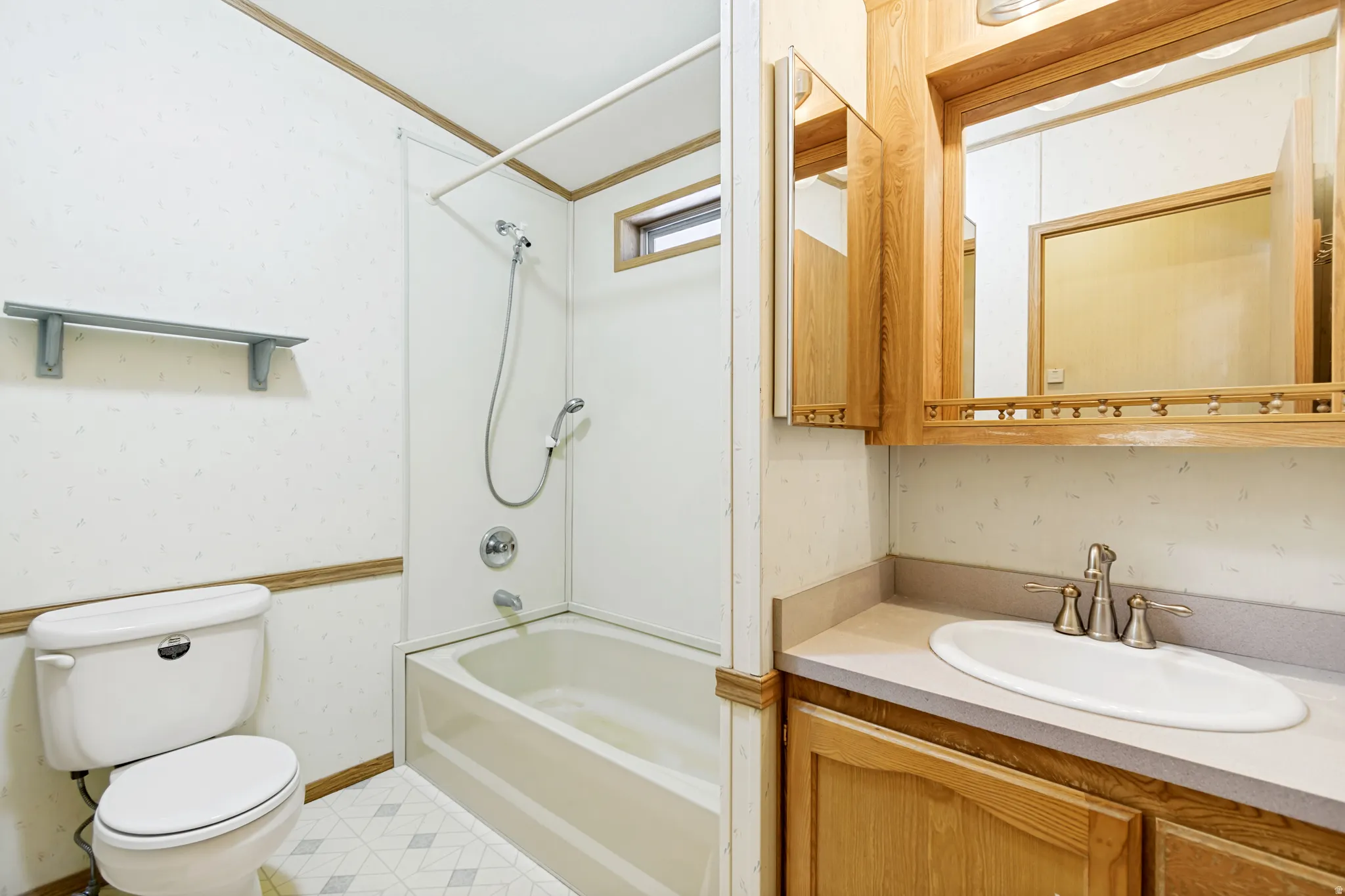 Bathroom with vanity, bathing tub / shower combination, and wallpapered walls