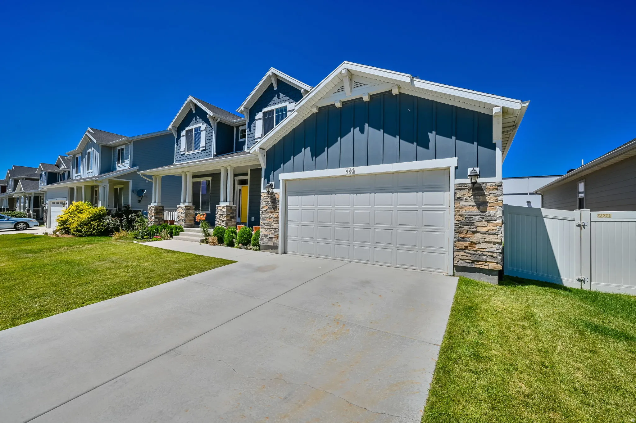 Contemporary home featuring blue siding with white trim, a stone façade, and an attached garage