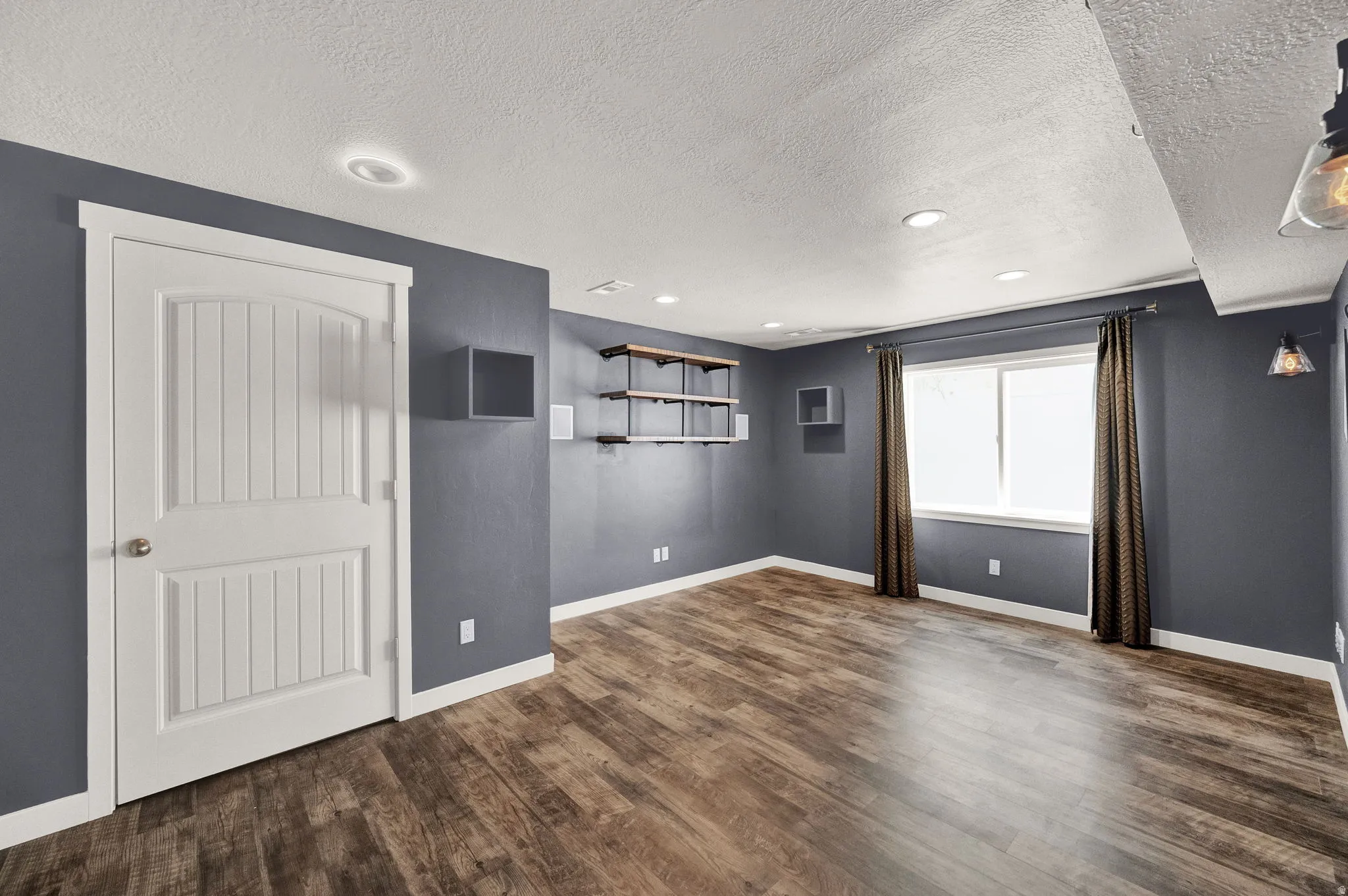 Spacious room featuring wood-finish flooring, recessed lighting, and a window with natural light