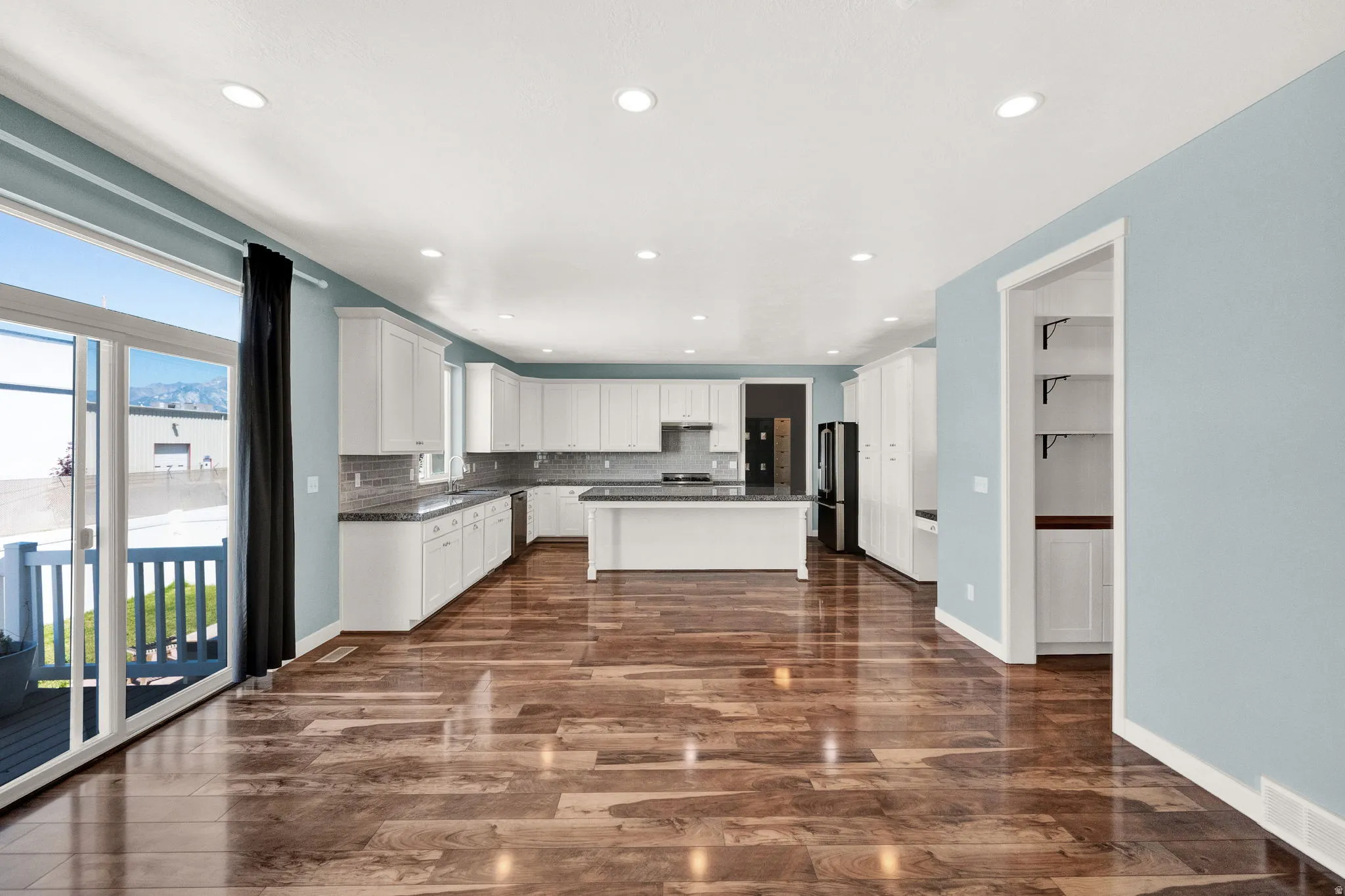 Open-concept living space featuring wood-finish flooring, recessed lighting, and a modern kitchen with white cabinetry