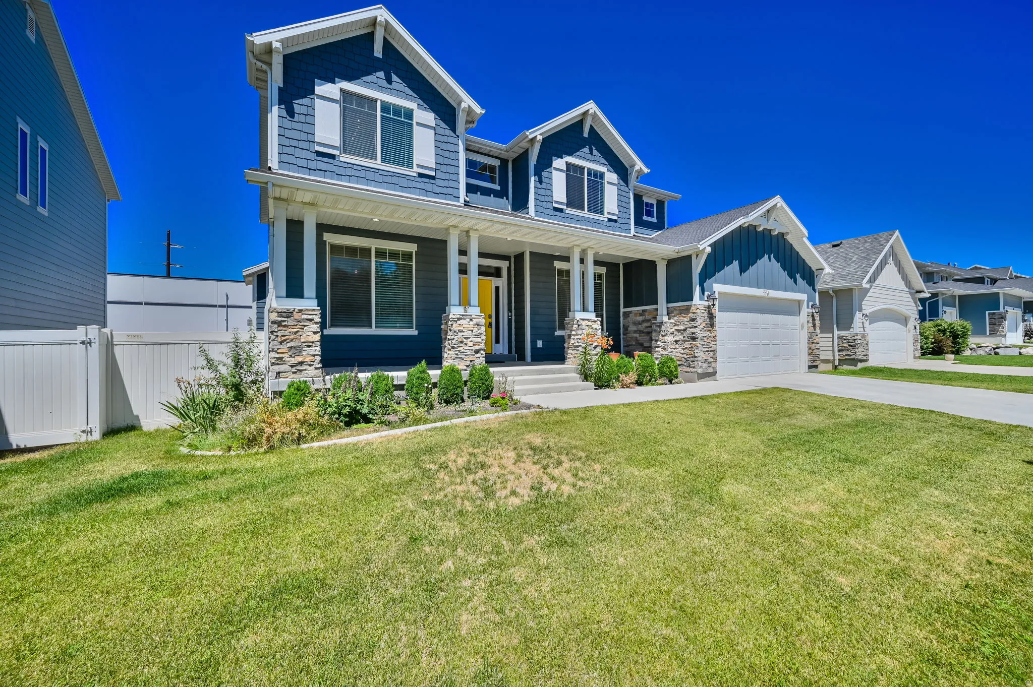 Two-story residence featuring blue siding, white trim, and stone accents