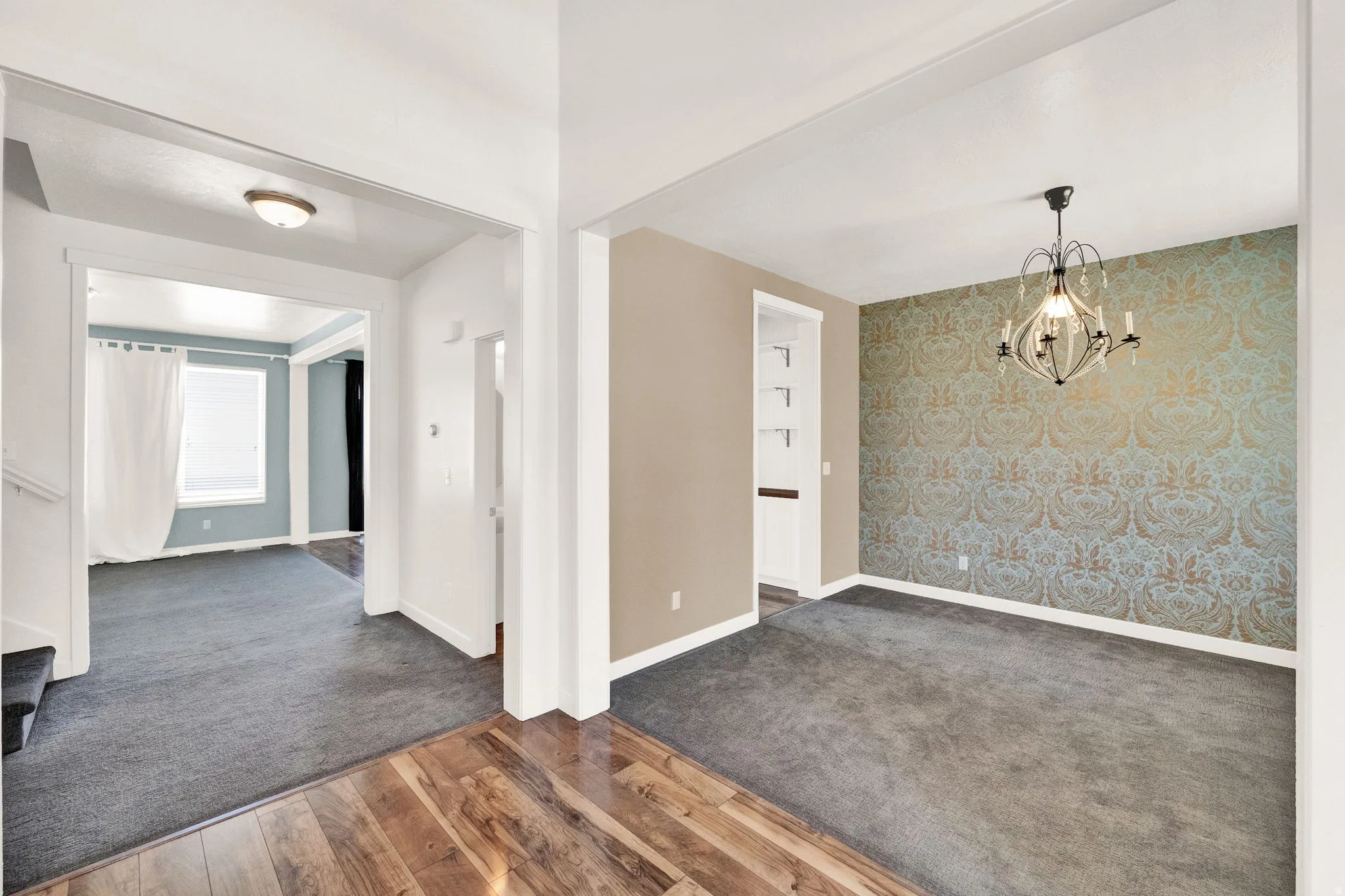Formal room featuring a statement wallpaper accent wall and an ornate chandelier