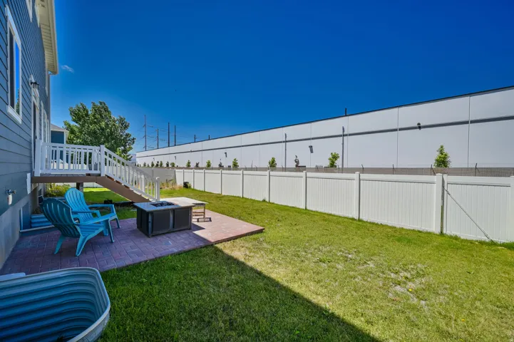 Spacious backyard featuring a brick paver patio, a full privacy fence, and a wooden deck with white railings