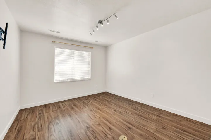 Spacious room with wood-finish flooring and white baseboards