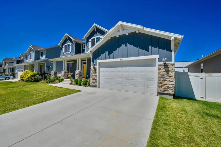 Contemporary home featuring blue siding with white trim, a stone façade, and an attached garage