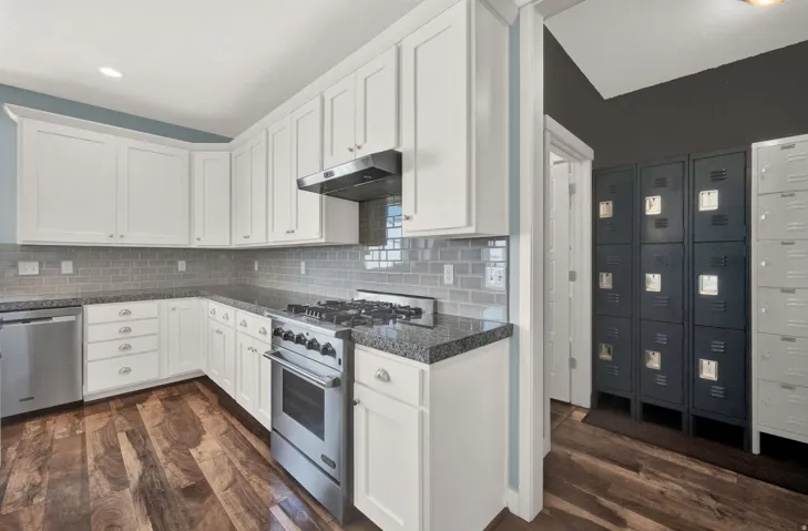 Kitchen featuring white shaker cabinetry, stainless steel appliances, granite countertops, and a subway tile backsplash
