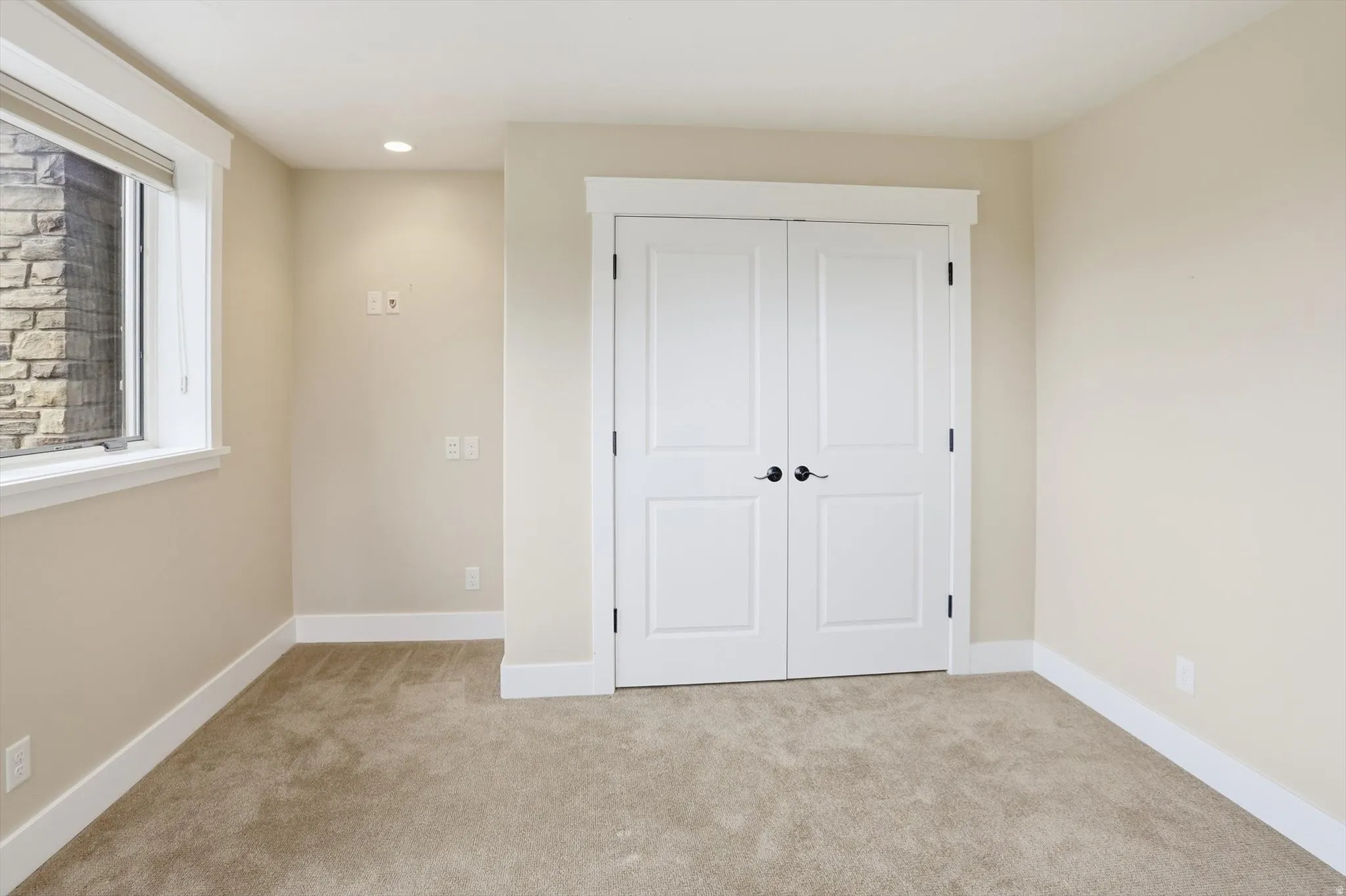 Neutral-toned room featuring plush carpet flooring and clean white baseboards