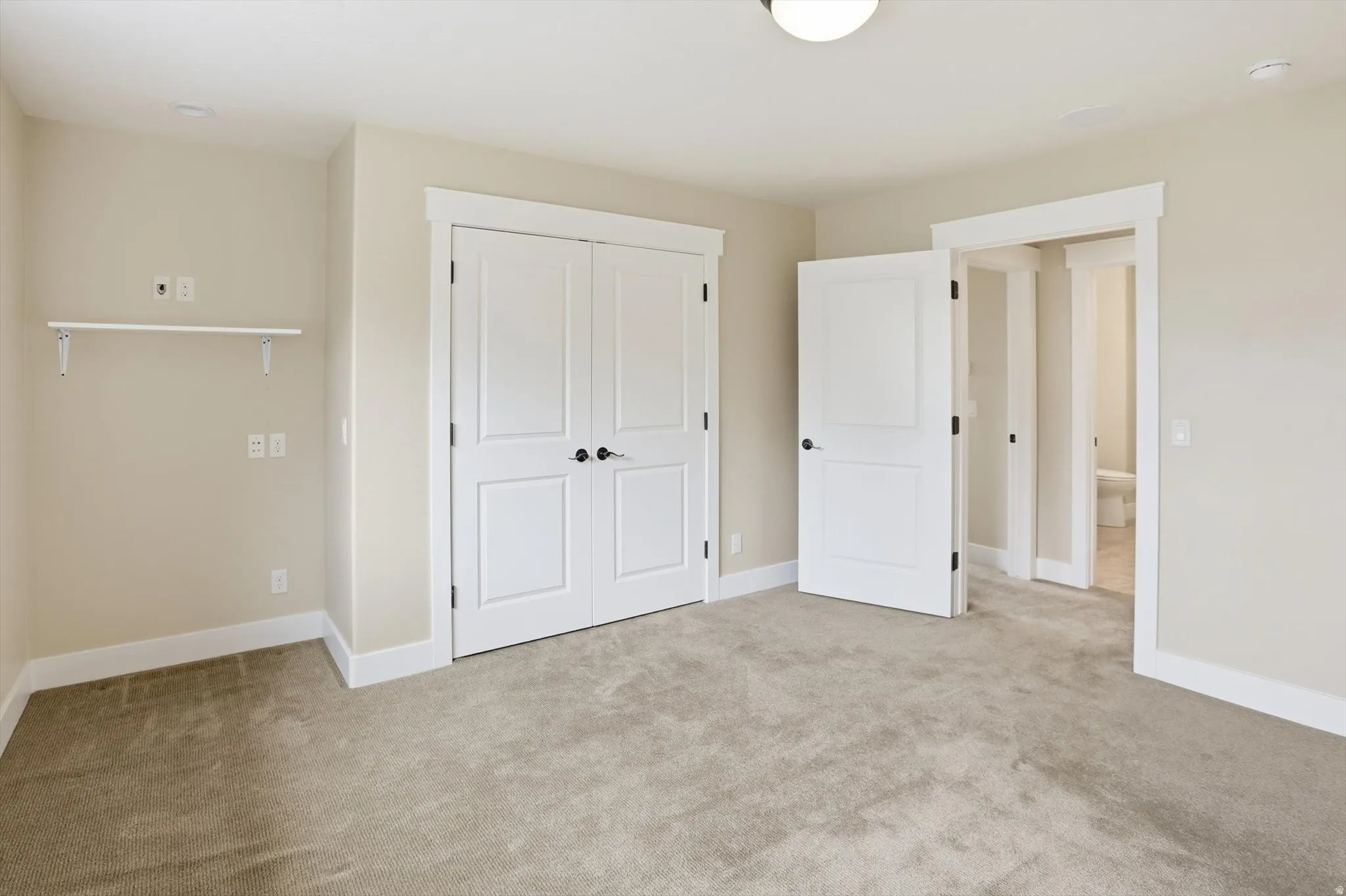 Neutral-toned room with plush carpeting, featuring white trim and baseboards