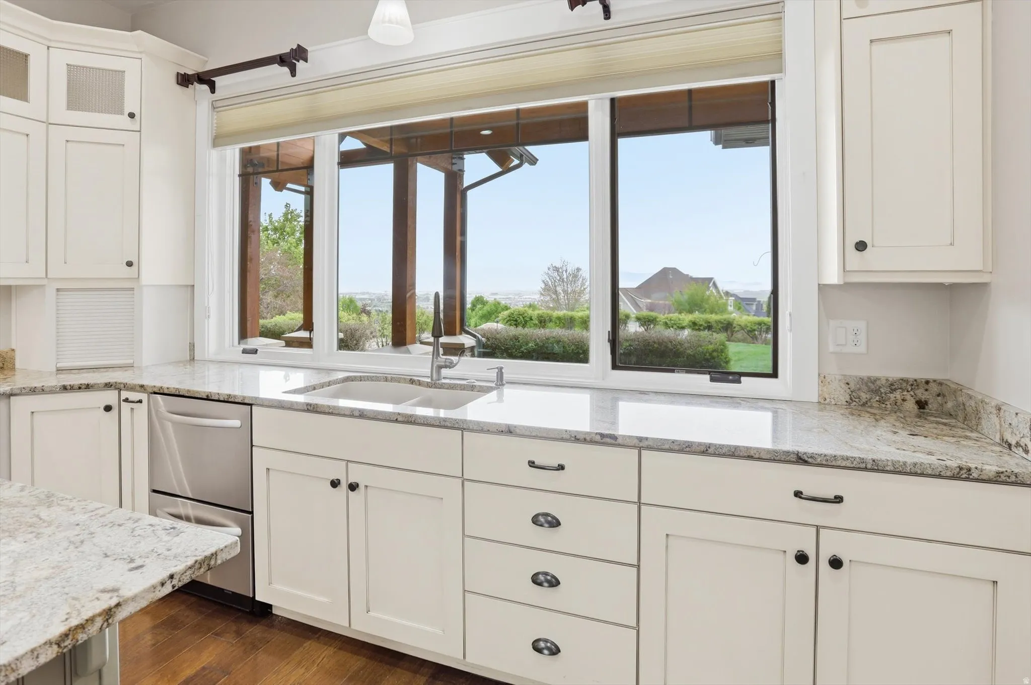 Kitchen featuring a stainless steel undermount sink with a gooseneck faucet, light-toned cabinetry, granite countertops, and wood-finish flooring