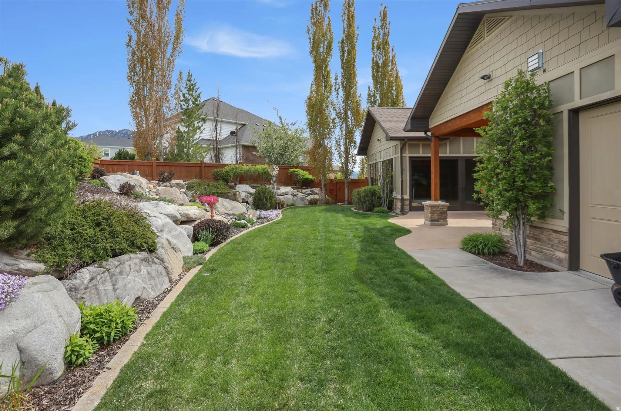Expansive green lawn bordering a tiered rock garden with diverse plantings