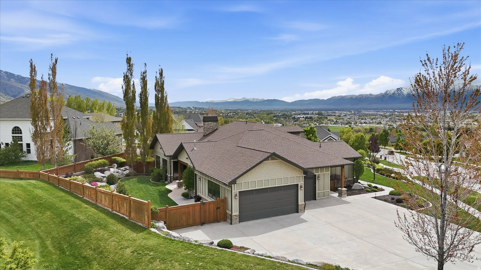 Single-story residence featuring a two-car garage, pitched roof, and a wood-slat privacy fence