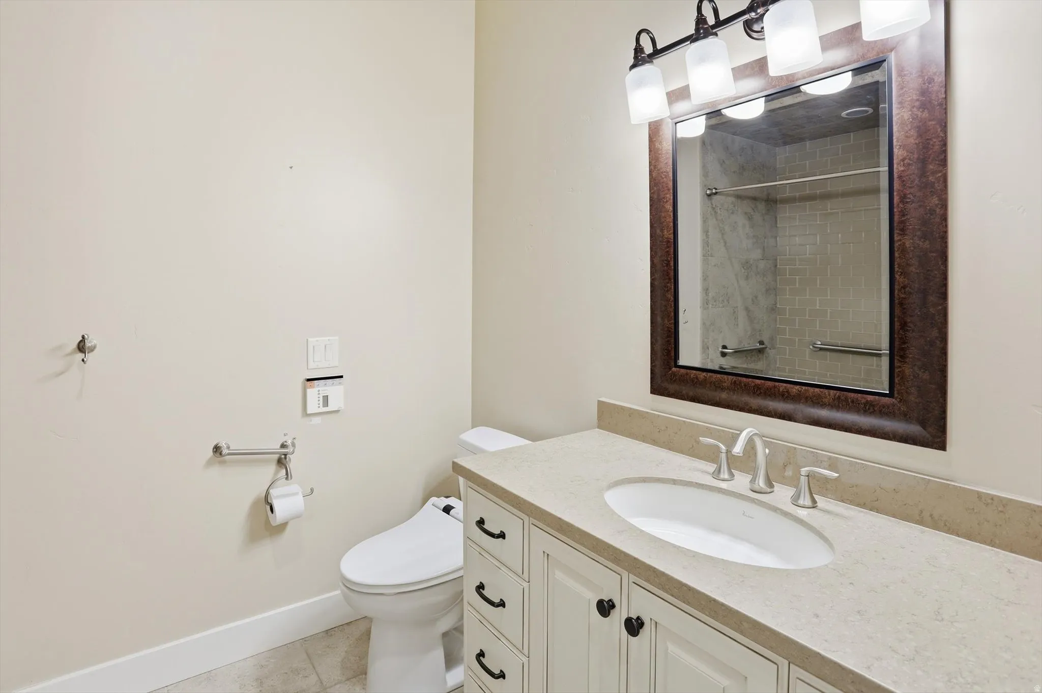 Vanity with an integrated oval sink, light-toned countertop, and white cabinetry with dark hardware