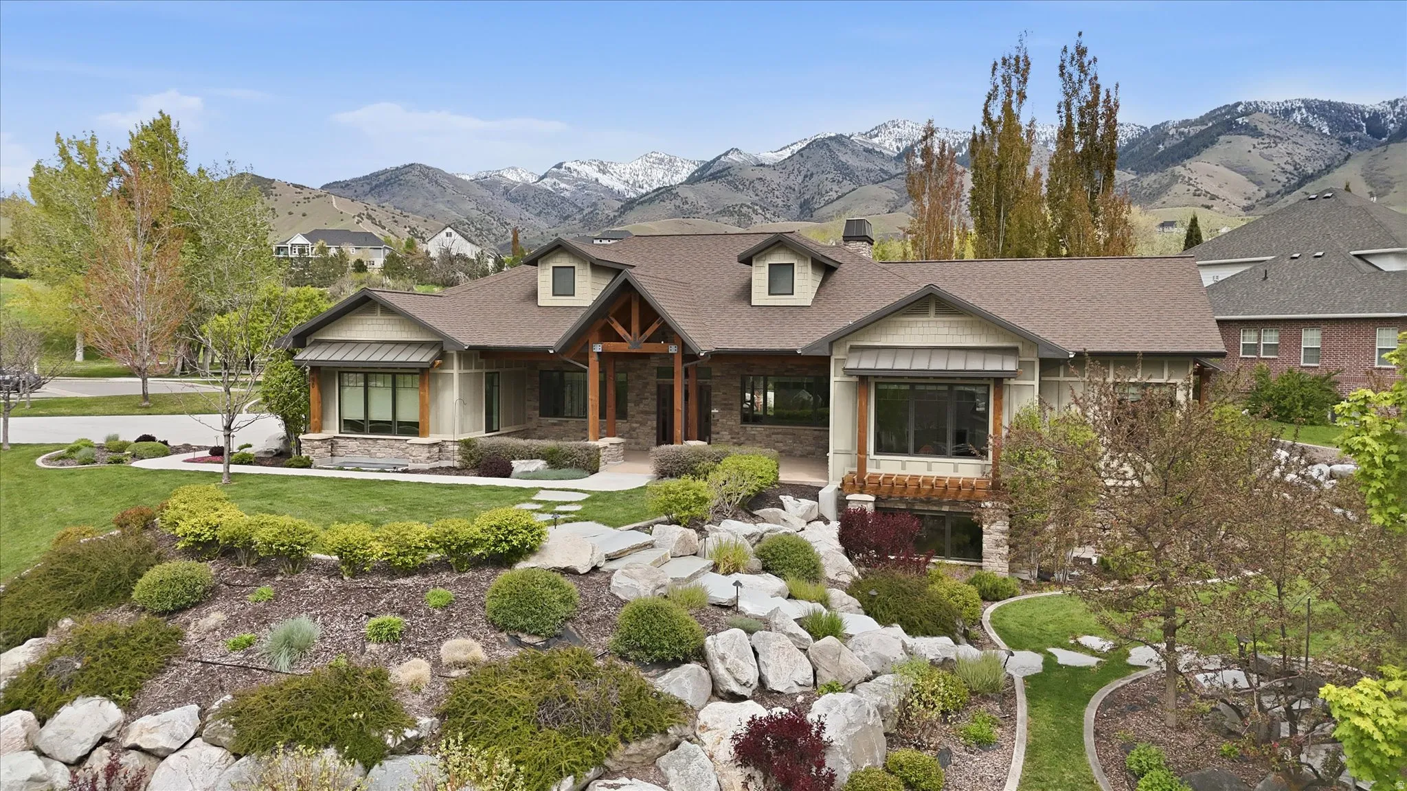 Craftsman-style residence featuring a stone and siding exterior, a prominent covered entry with timber detailing, and dormer windows