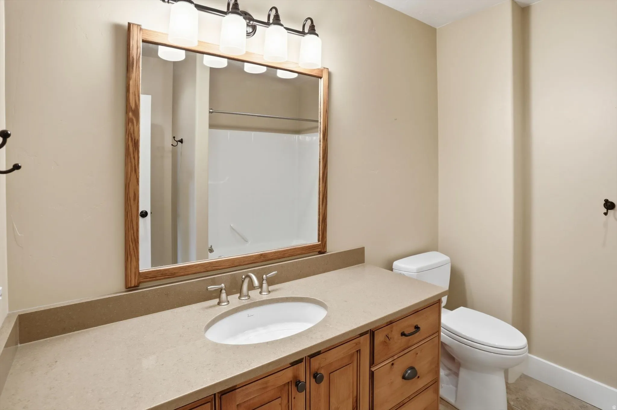 Bathroom featuring a vanity with wood cabinetry, a light-toned countertop, and an undermount sink with a brushed nickel faucet