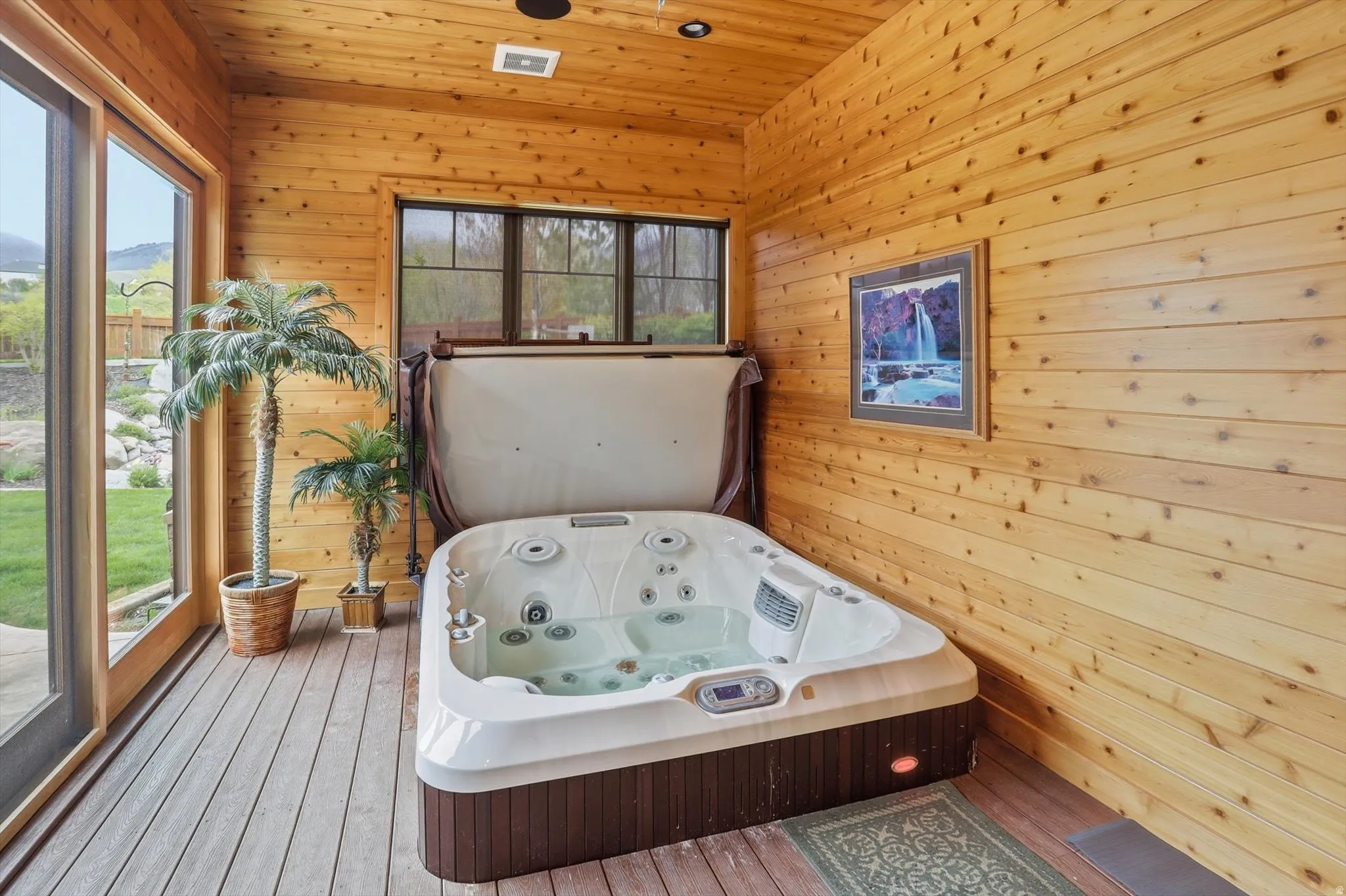 Indoor spa room featuring a built-in spa, wood-paneled walls and ceiling, wood-finish flooring, and multi-pane windows
