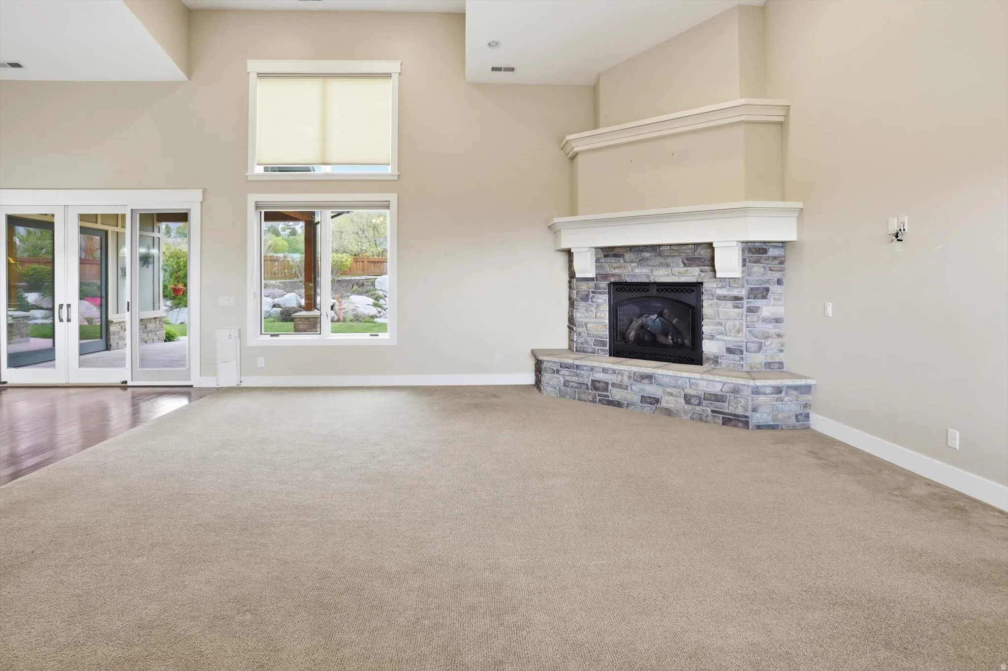 Spacious interior featuring a stone-clad fireplace with a decorative mantel, neutral carpeting, and high ceilings