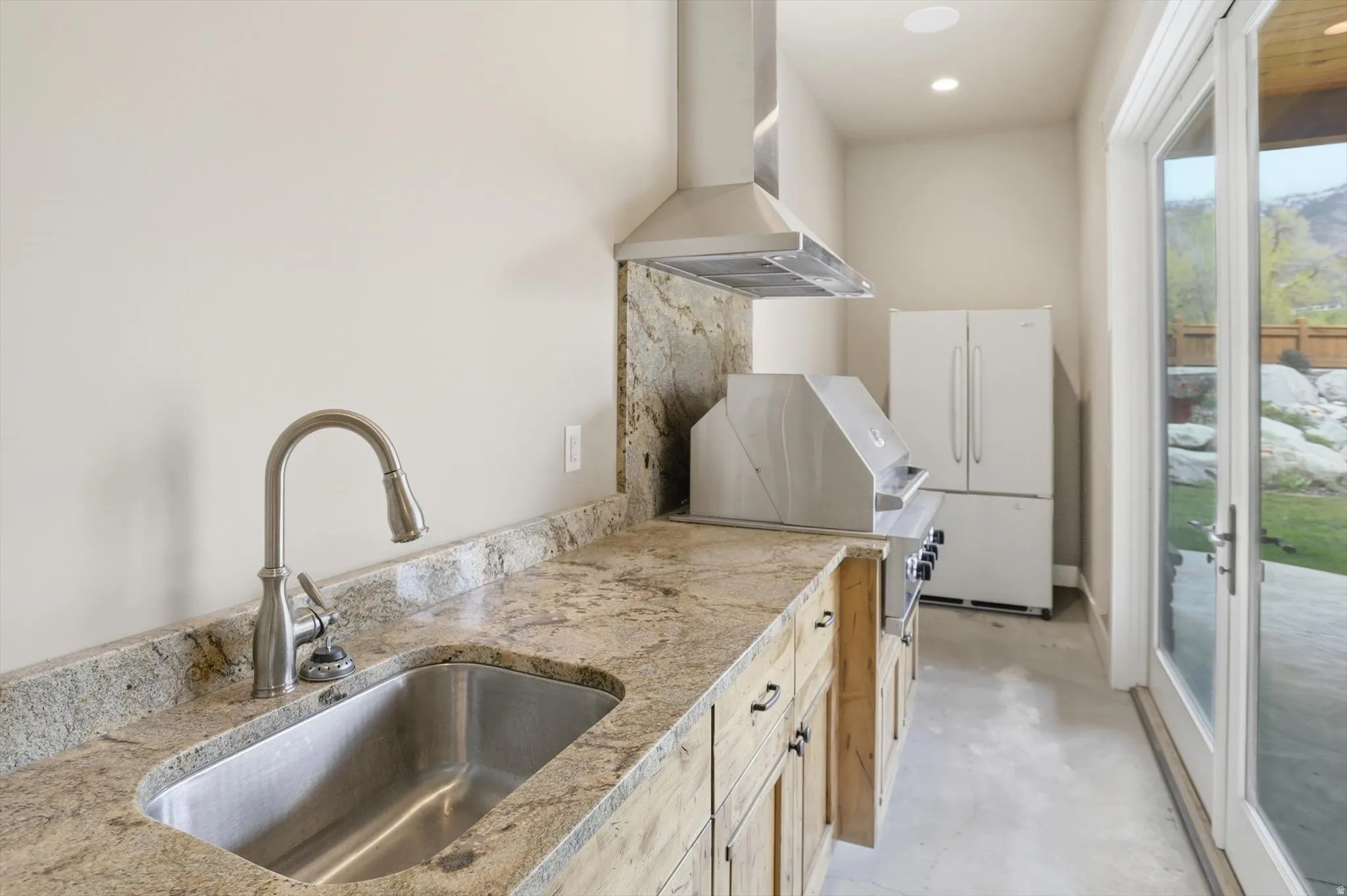 Outdoor kitchen featuring a built-in stainless steel grill, granite countertops, and a stainless steel sink with a gooseneck faucet