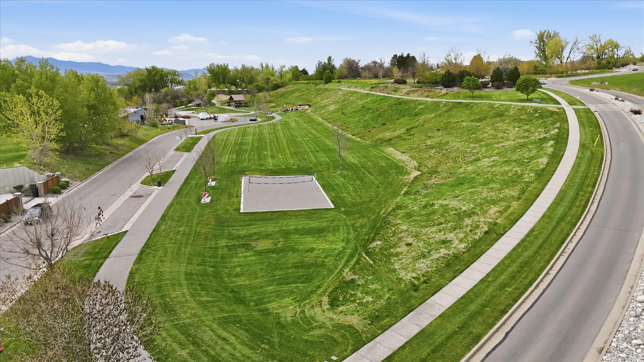 Expansive green space featuring a level, rectangular hardcourt area surrounded by lush lawn