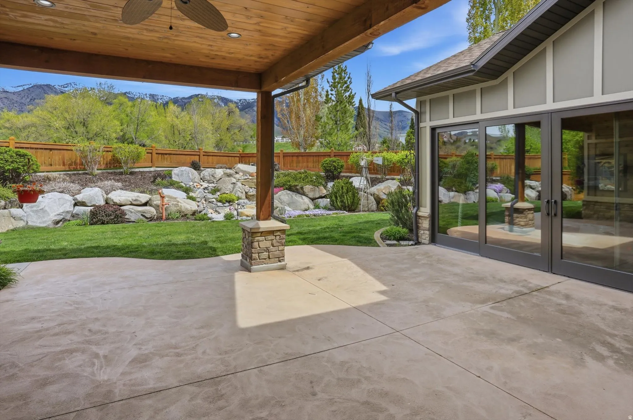 Expansive concrete patio under a wood-finish covered ceiling with a ceiling fan