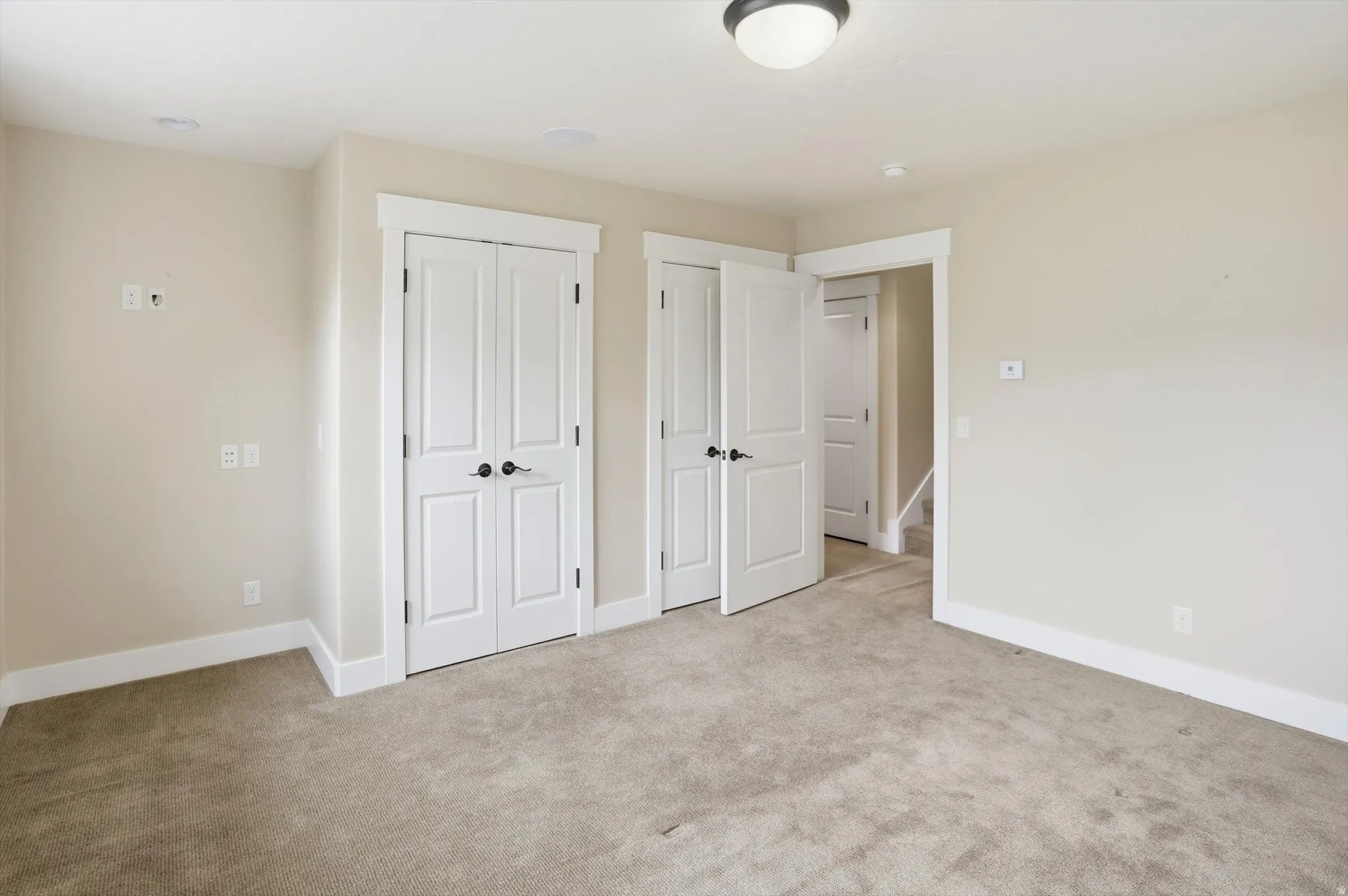 Neutral-toned interior room featuring light beige walls and light brown carpet flooring