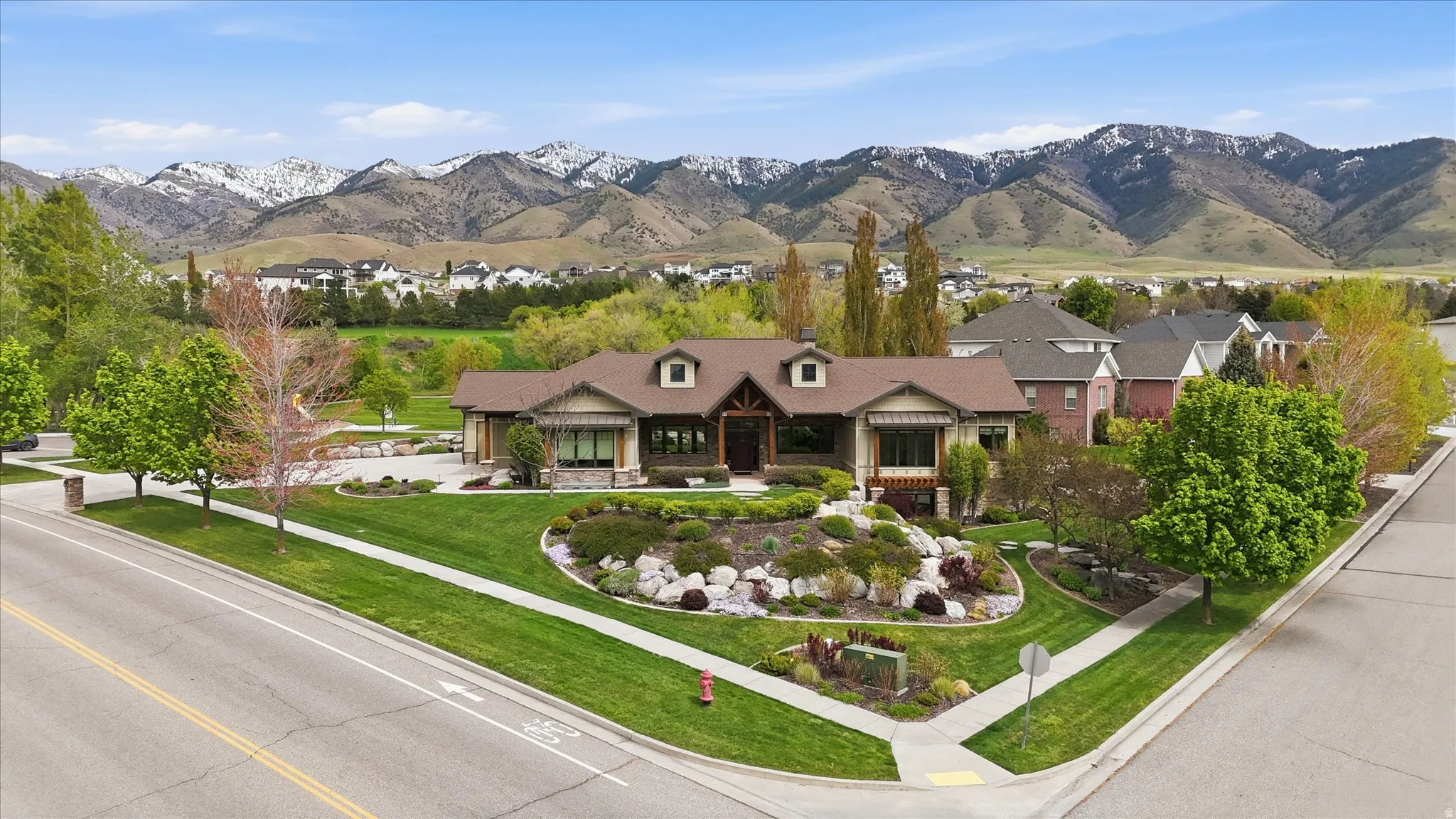Craftsman-style residence with a stone and wood facade, featuring a prominent gable roof and dormer windows