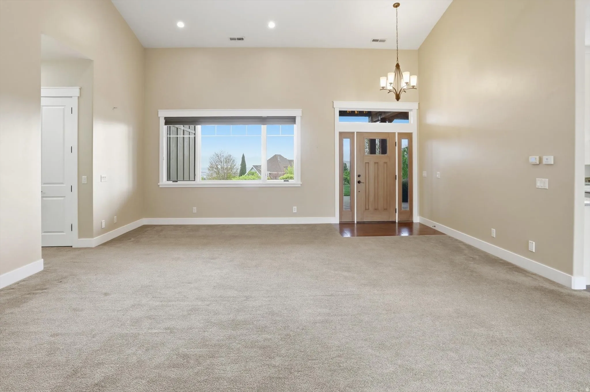 Spacious living area featuring neutral carpeting and high vaulted ceilings
