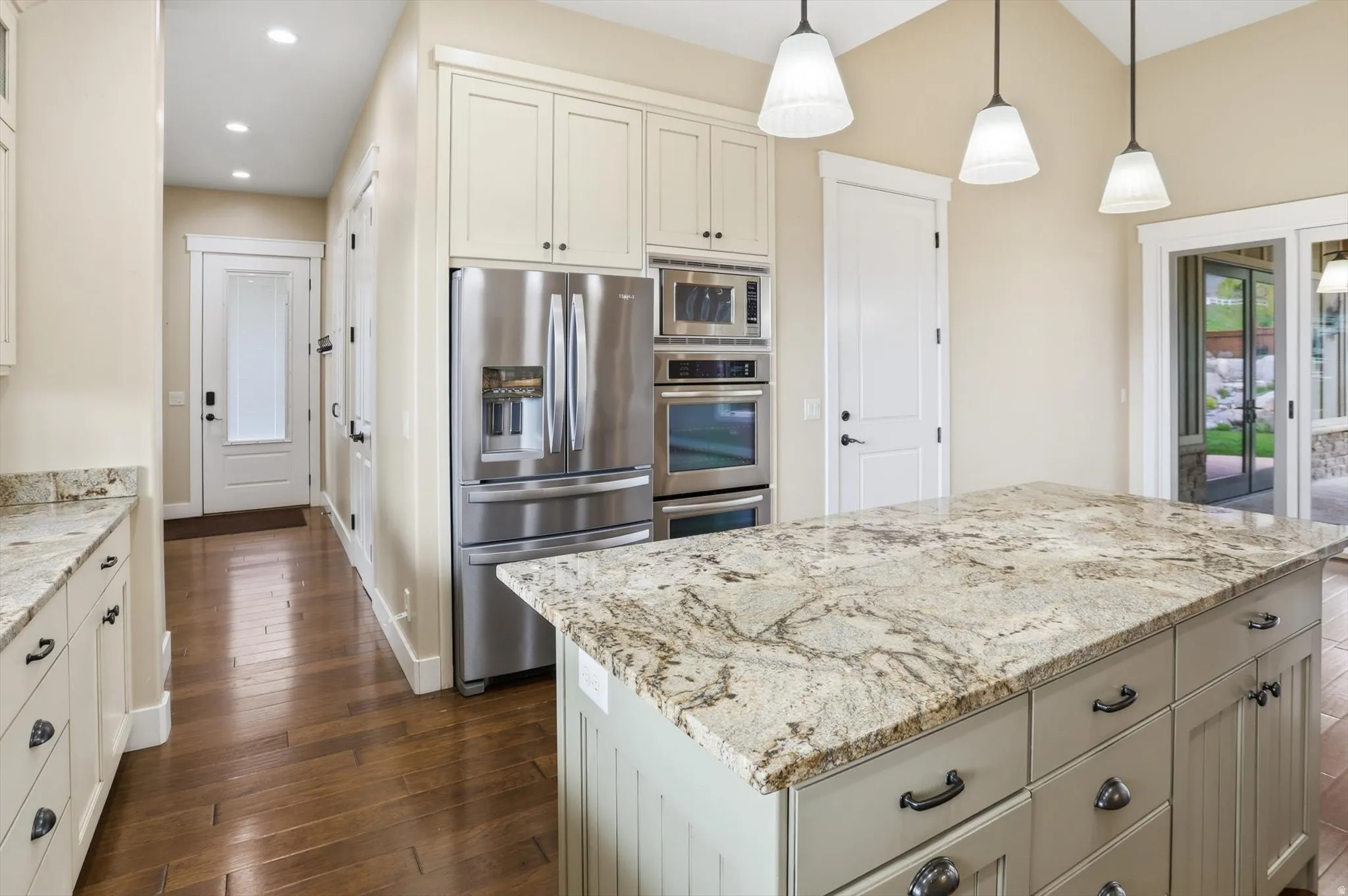 Kitchen featuring a substantial island with a patterned countertop, wood-finish flooring, and recessed lighting