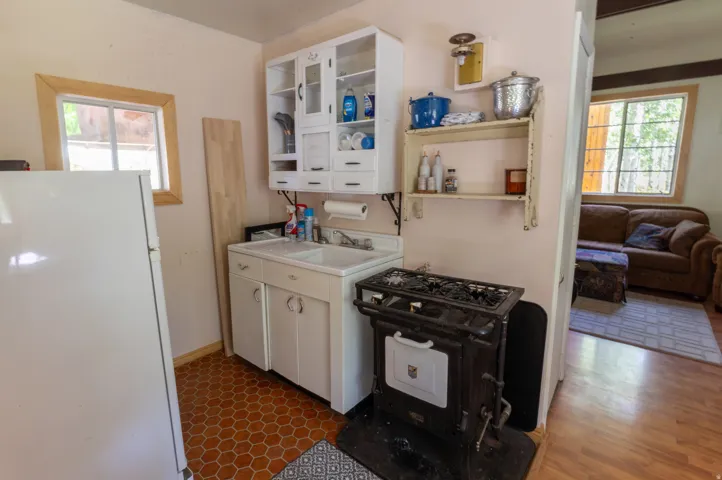 Kitchen space featuring hexagonal tile flooring, a white porcelain sink, an antique-style stove, and a wall-mounted cabinet with glass doors