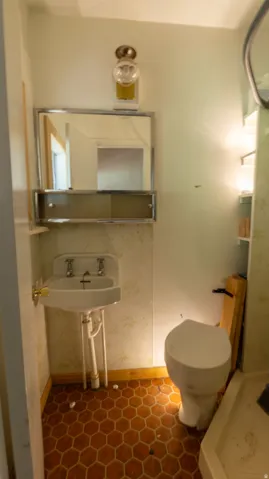 Pedestal sink with dual faucets, wall-mounted mirror cabinet, and hexagonal tile flooring
