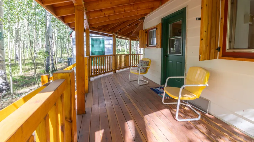 Expansive covered wood deck featuring natural wood railing and support beams