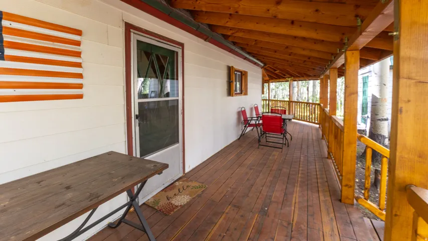 Expansive covered porch featuring wood-finish flooring, exposed wood beams, and natural wood railing