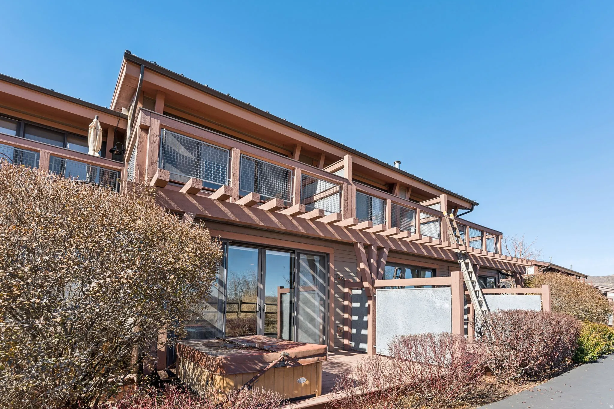 Multi-level exterior featuring a ground-floor patio, an upper-level balcony, and a pergola structure