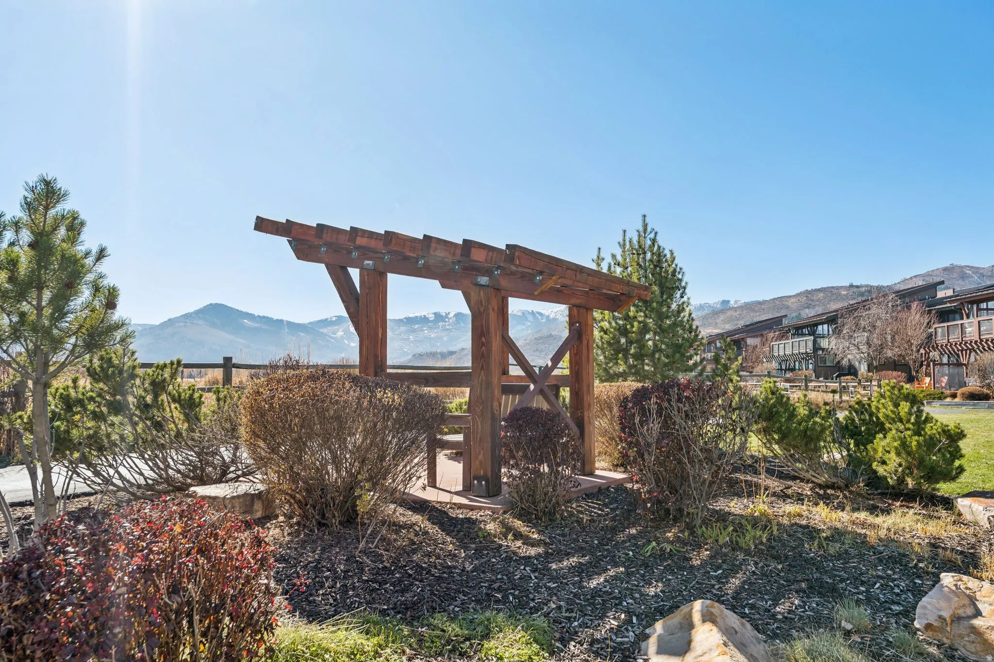 Wood pergola structure with mountain backdrop, surrounded by established landscaping