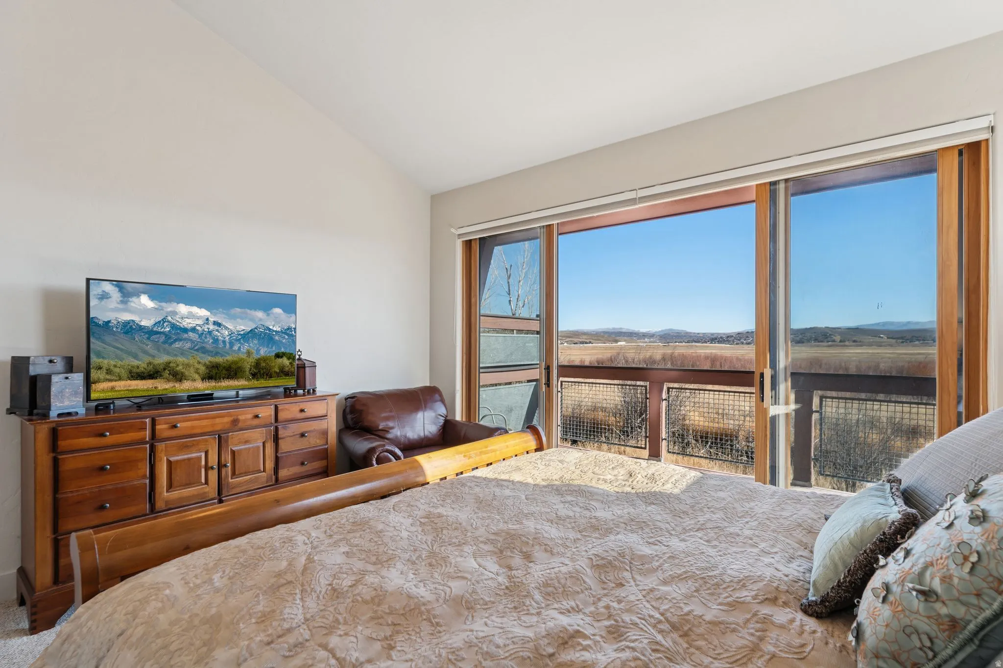 Vaulted ceiling bedroom featuring expansive sliding glass doors opening to a private balcony