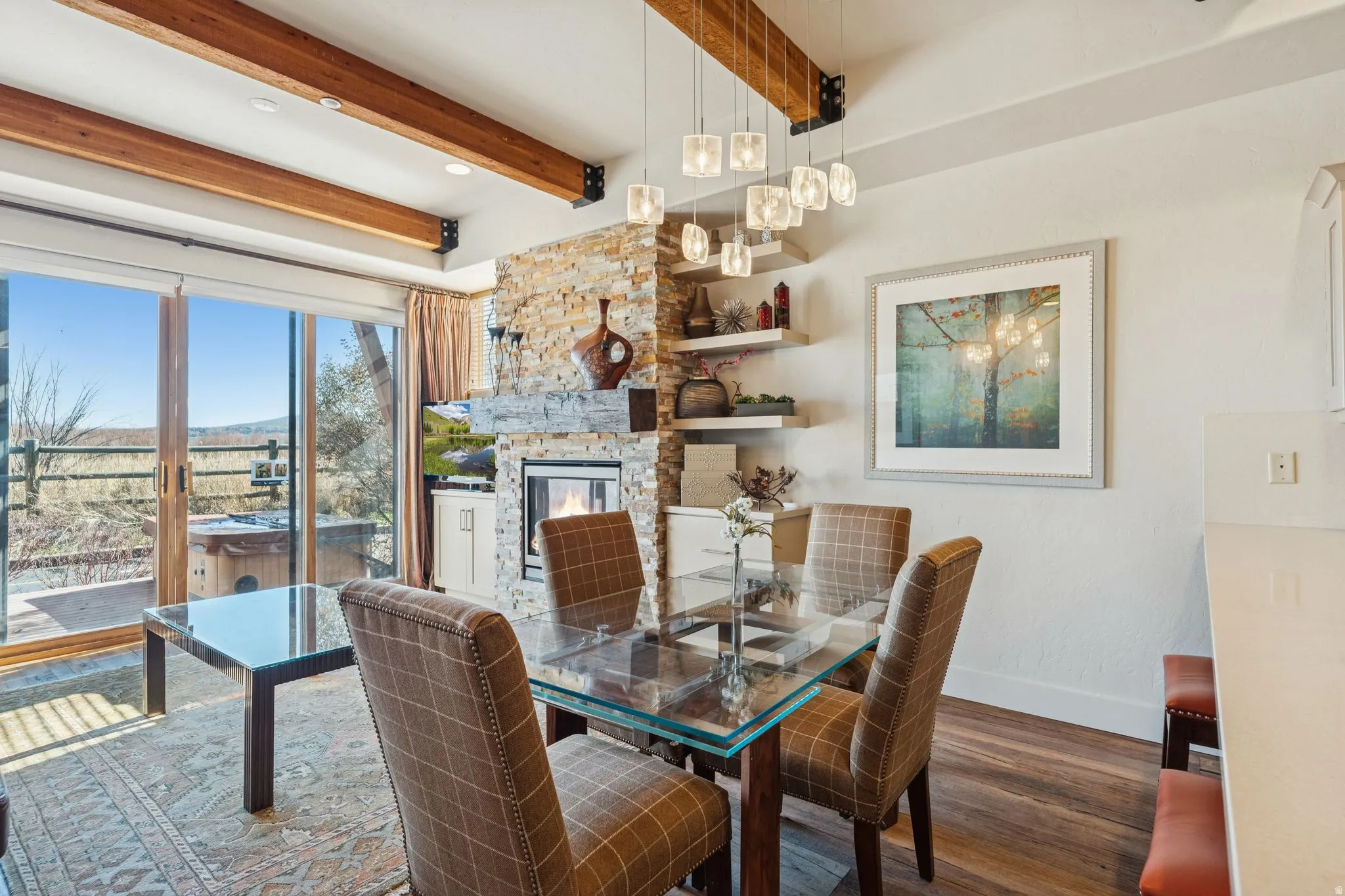 Dining area featuring a stone accent wall, fireplace with an integrated television, and a glass-top dining table