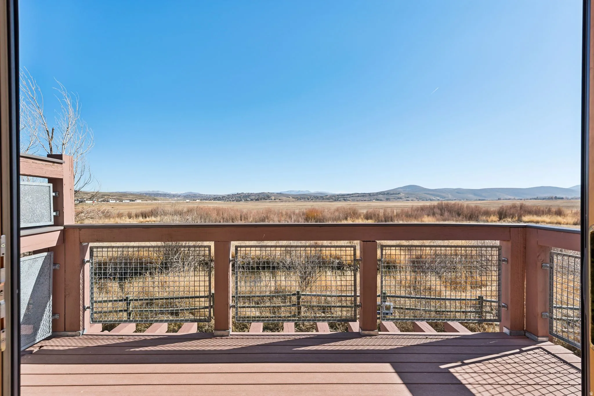 Outdoor deck featuring composite decking, wood railing with metal grid inserts, and expansive natural landscape