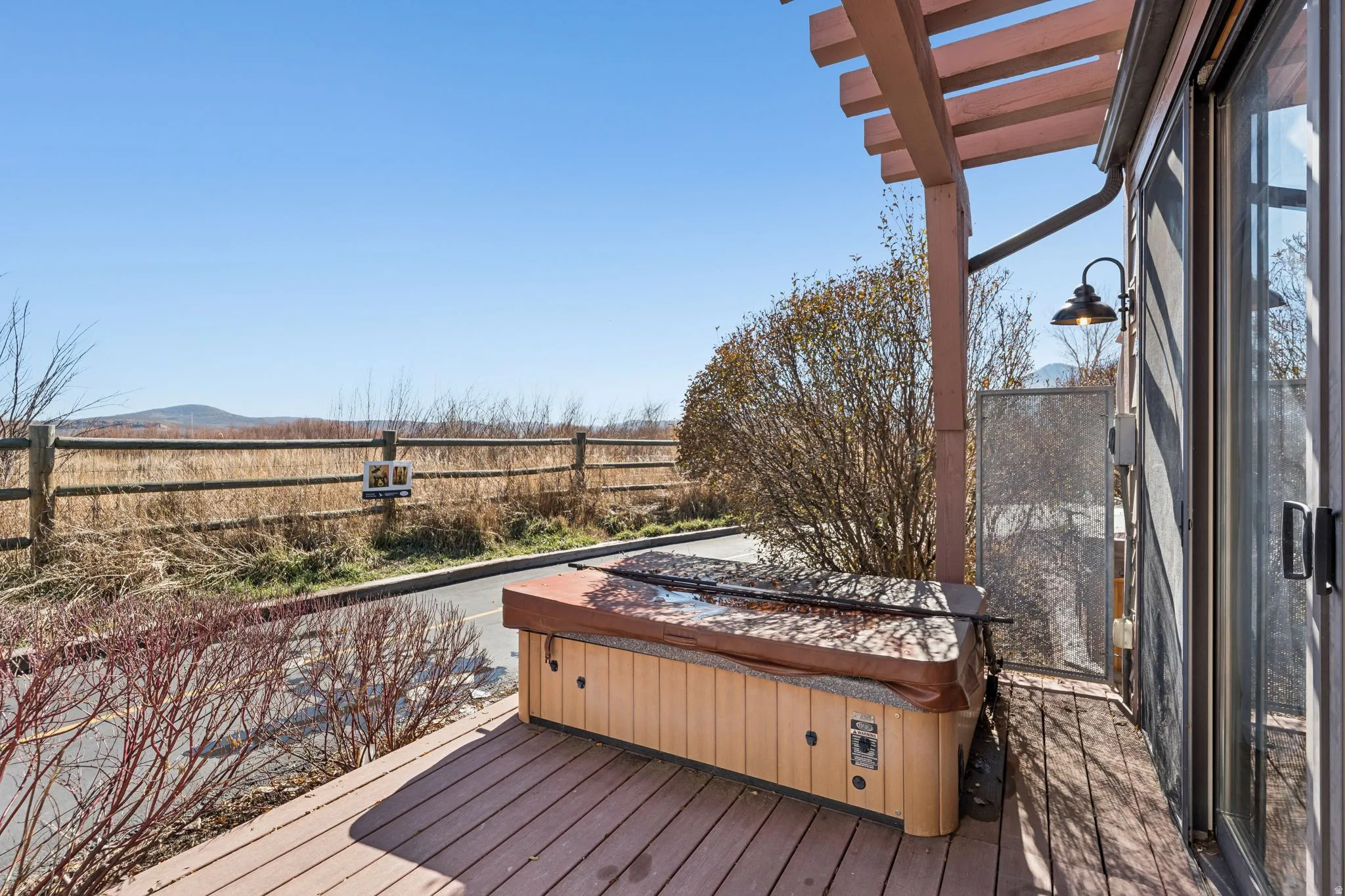 Expansive outdoor deck featuring a hot tub, wood pergola, and sliding glass door access