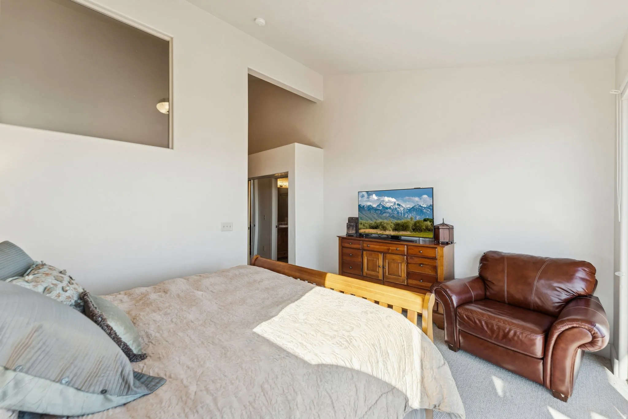 Bedroom featuring a wood-finish dresser, neutral carpeting, and high ceilings