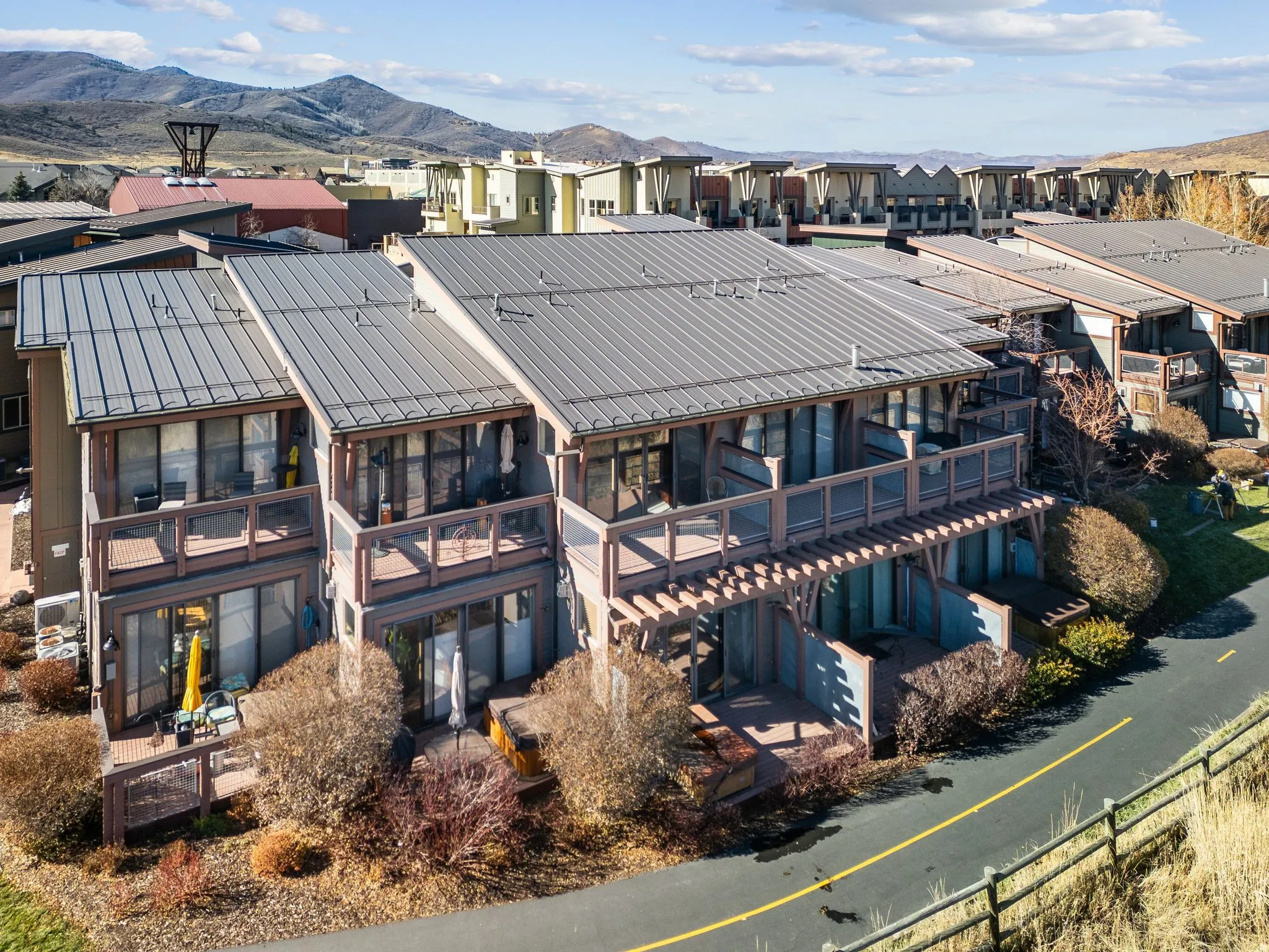 Multi-level residential structure featuring metal roofs, extensive glass doors, and multiple balconies