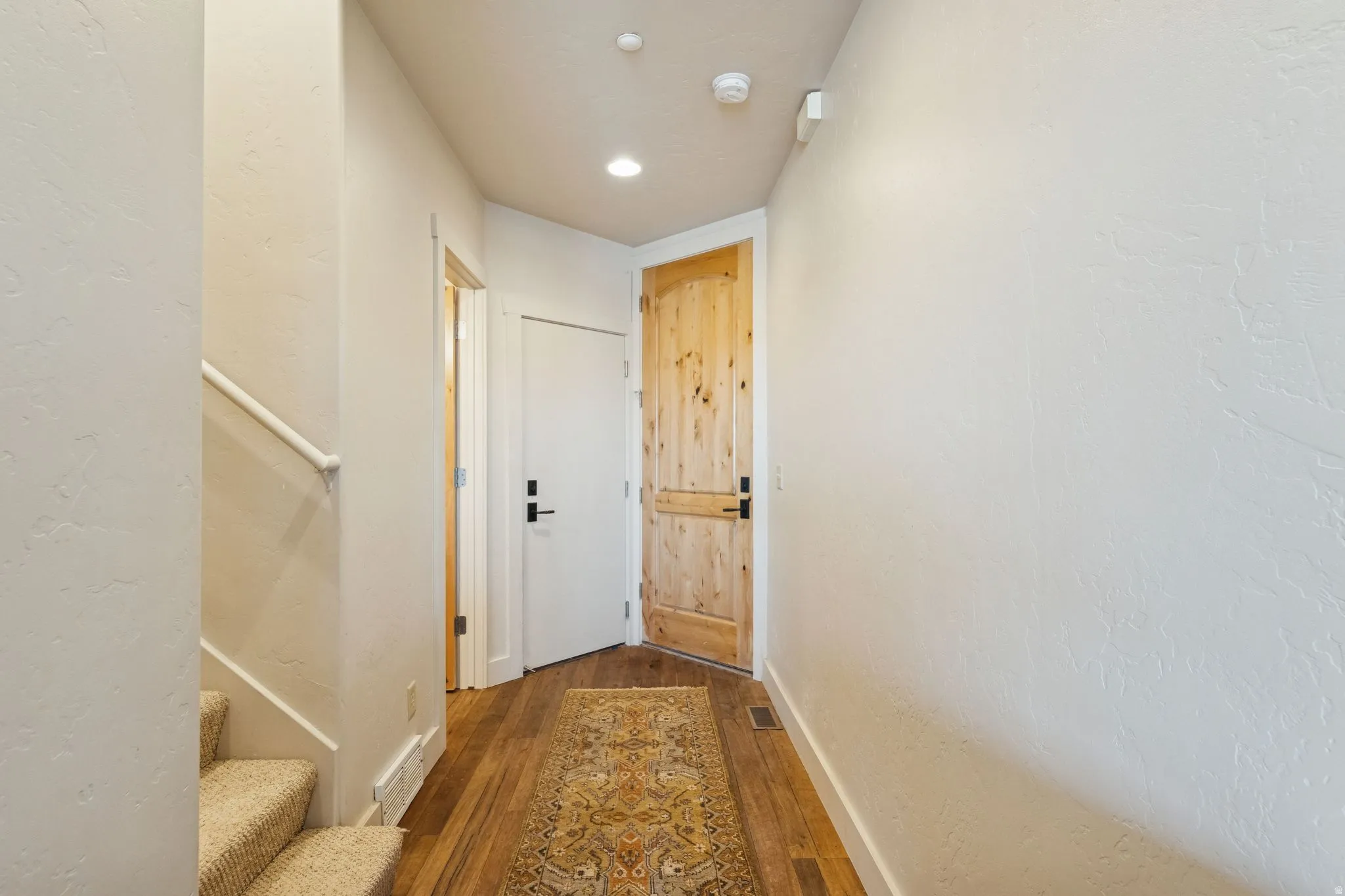 Entryway featuring natural wood-finish flooring, recessed lighting, and a solid wood door with black hardware