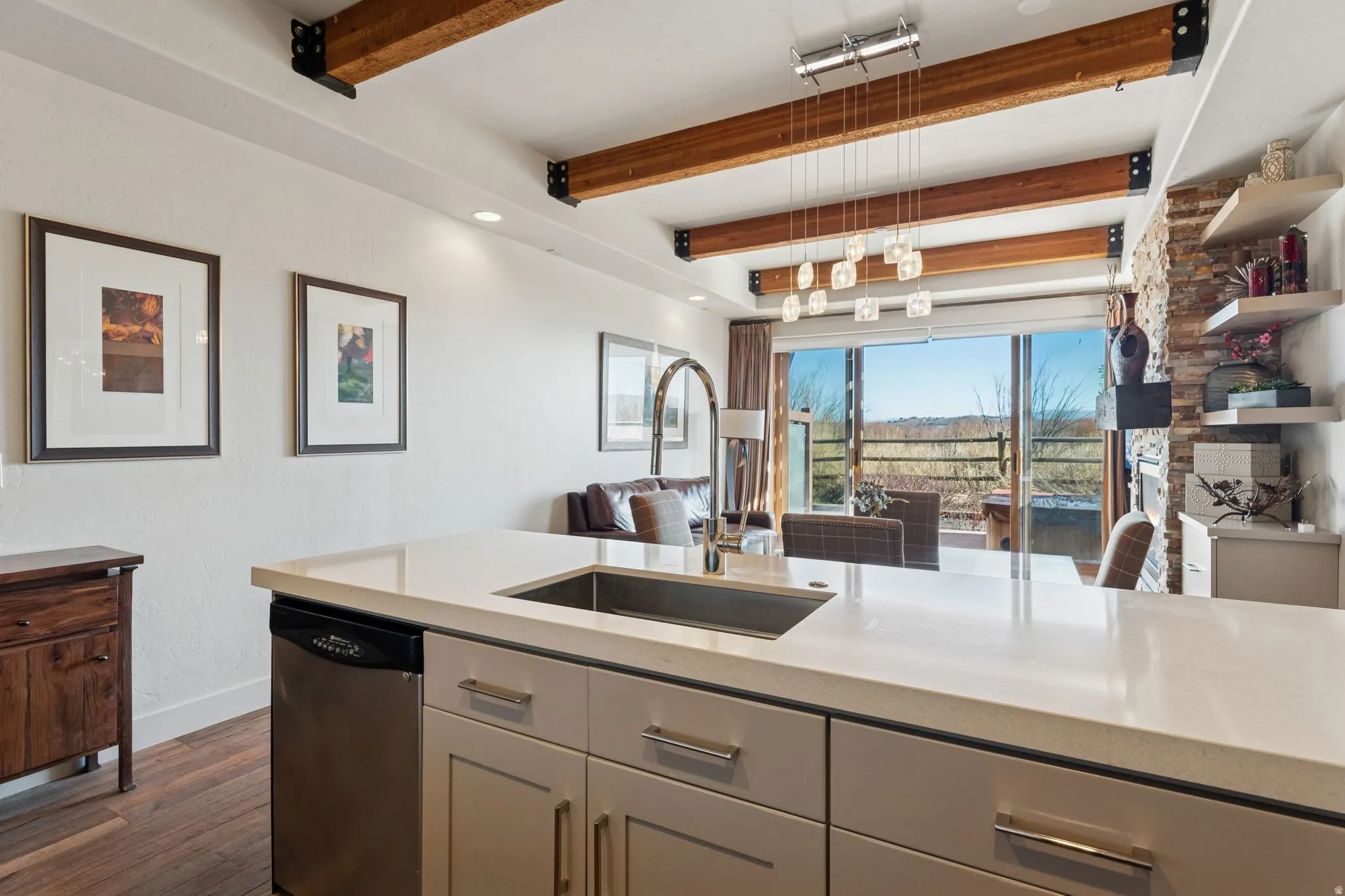 Kitchen island featuring a stainless steel sink, integrated dishwasher, and light-toned cabinetry with contemporary hardware