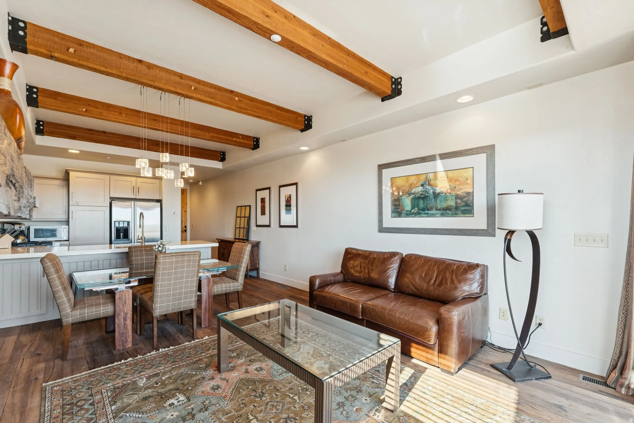 Open-concept living area with exposed wood ceiling beams and recessed lighting